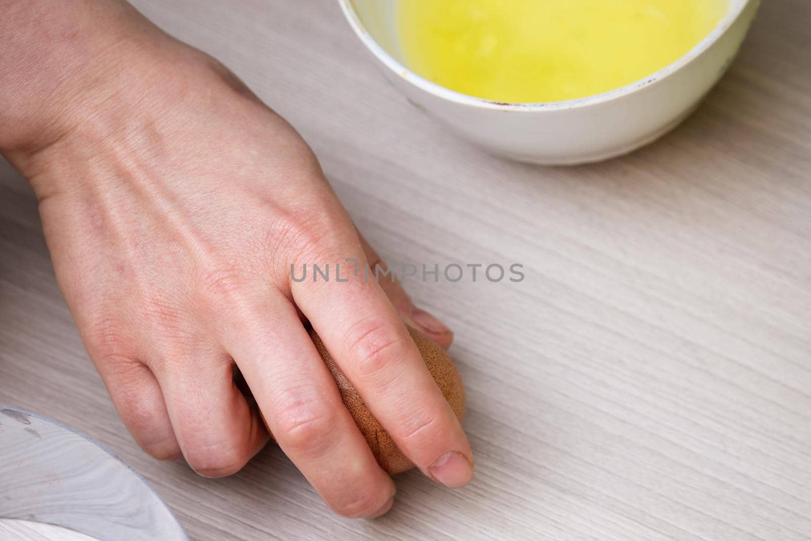 Close-up woman's hands break the egg and separate the white from the yolk.