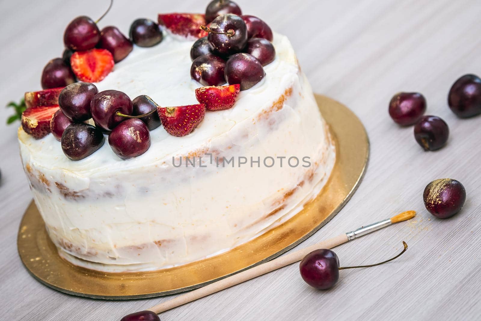 Cherries and strawberries with edible gold on top of cheesecake with coconut.