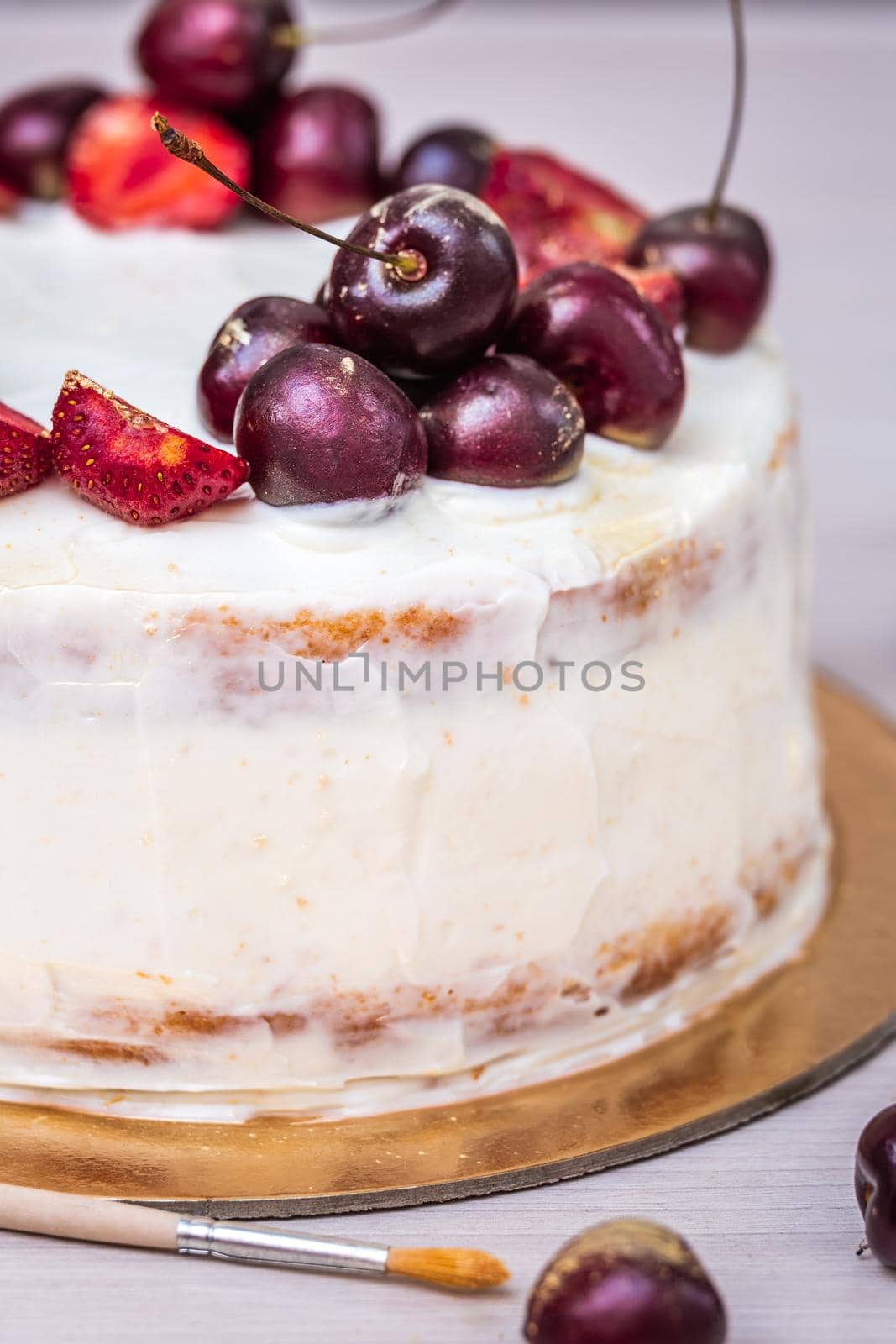 Cherries and strawberries with edible gold on top of cheesecake with coconut.