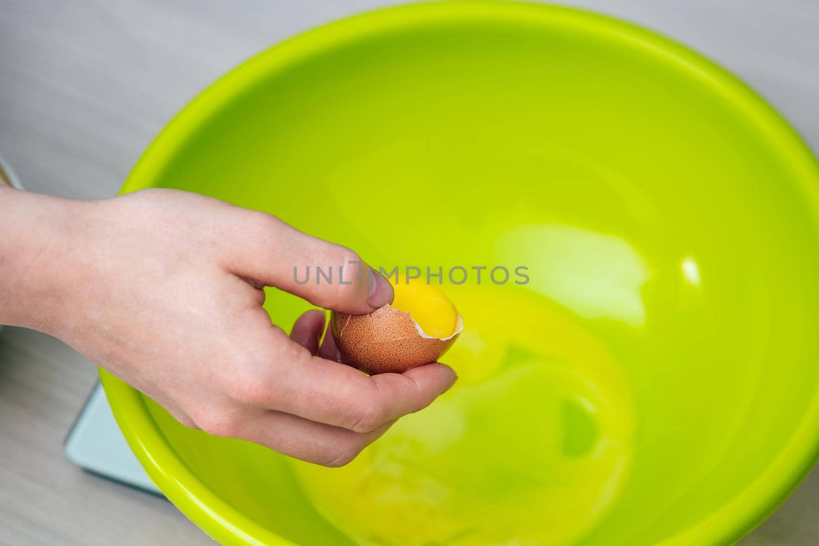 Close-up woman's hands break the egg and separate the white from the yolk.