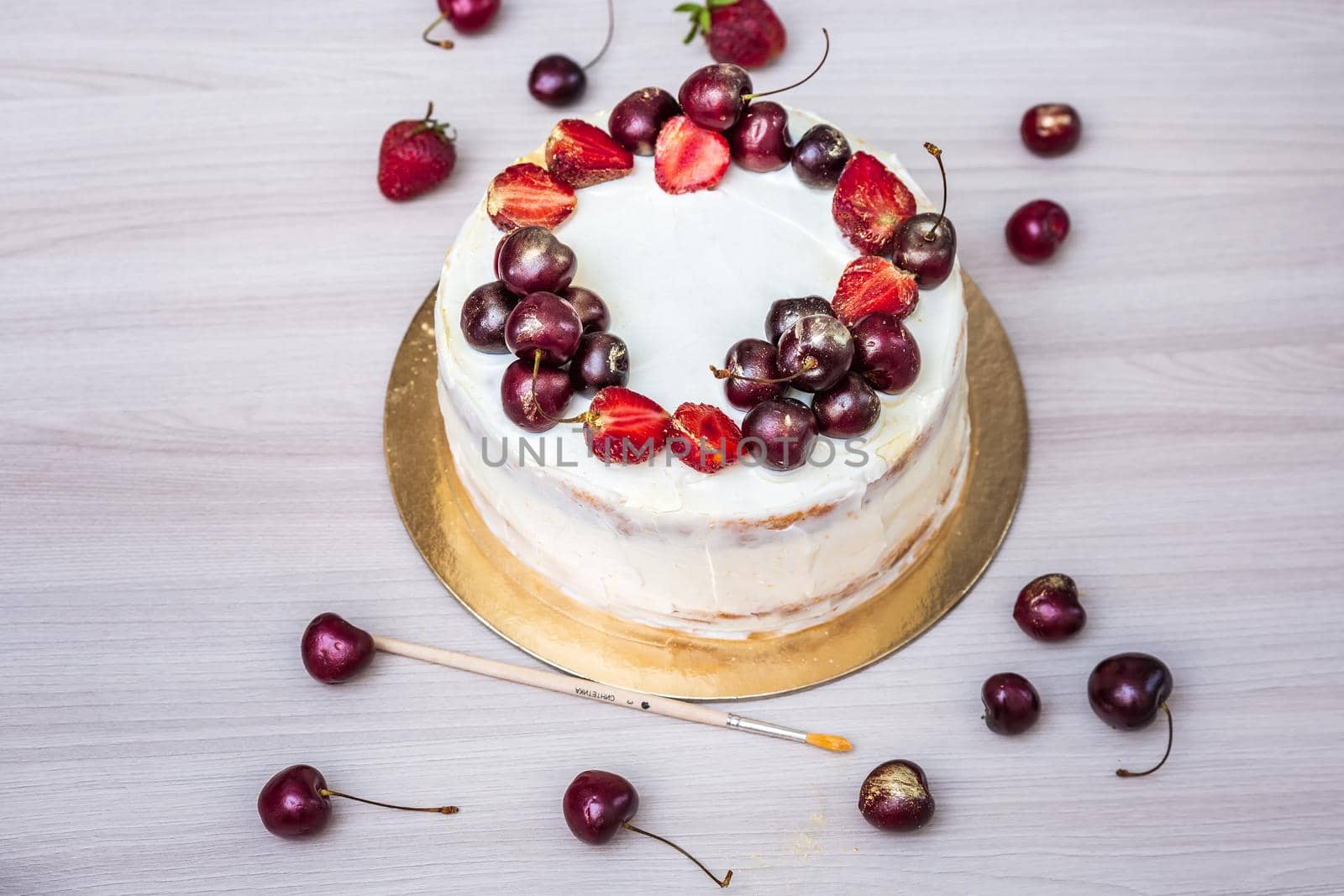 Cherries and strawberries with edible gold on top of cheesecake with coconut.