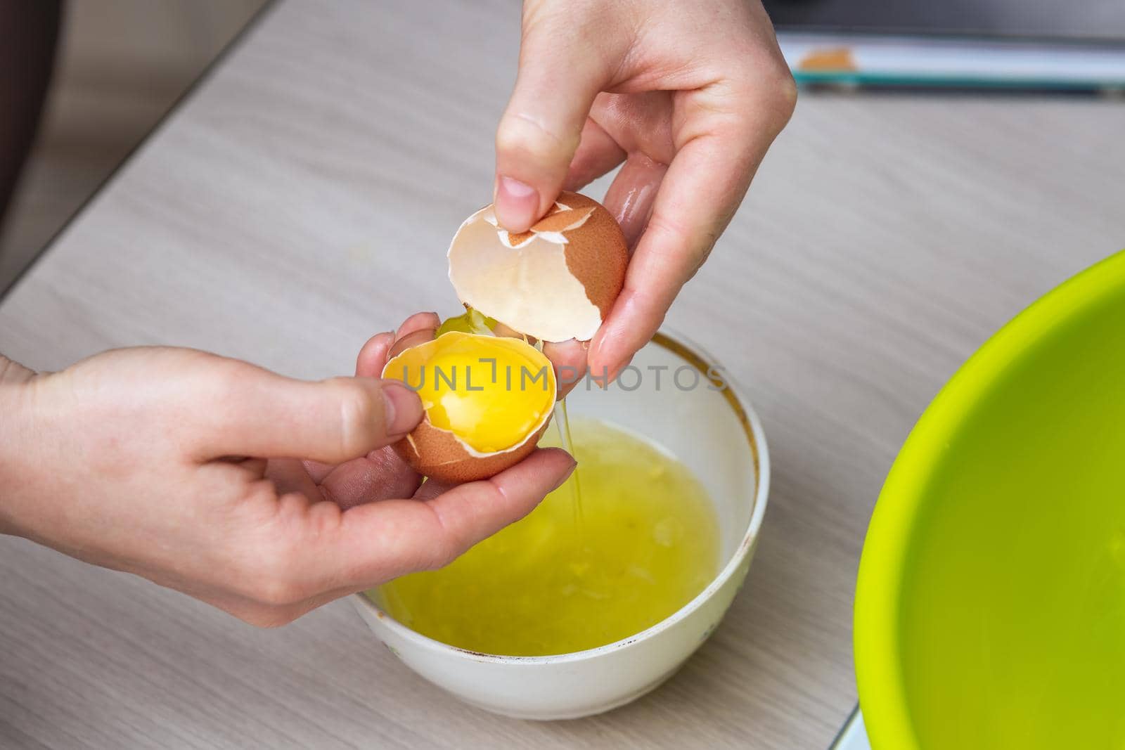 Close-up woman's hands break the egg and separate the white from the yolk.