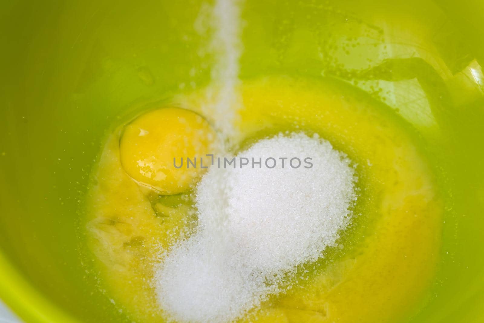 Adding sugar to the eggs and making homemade cake.