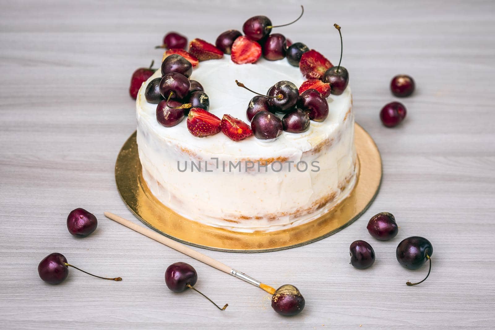 Cherries and strawberries with edible gold on top of cheesecake with coconut.