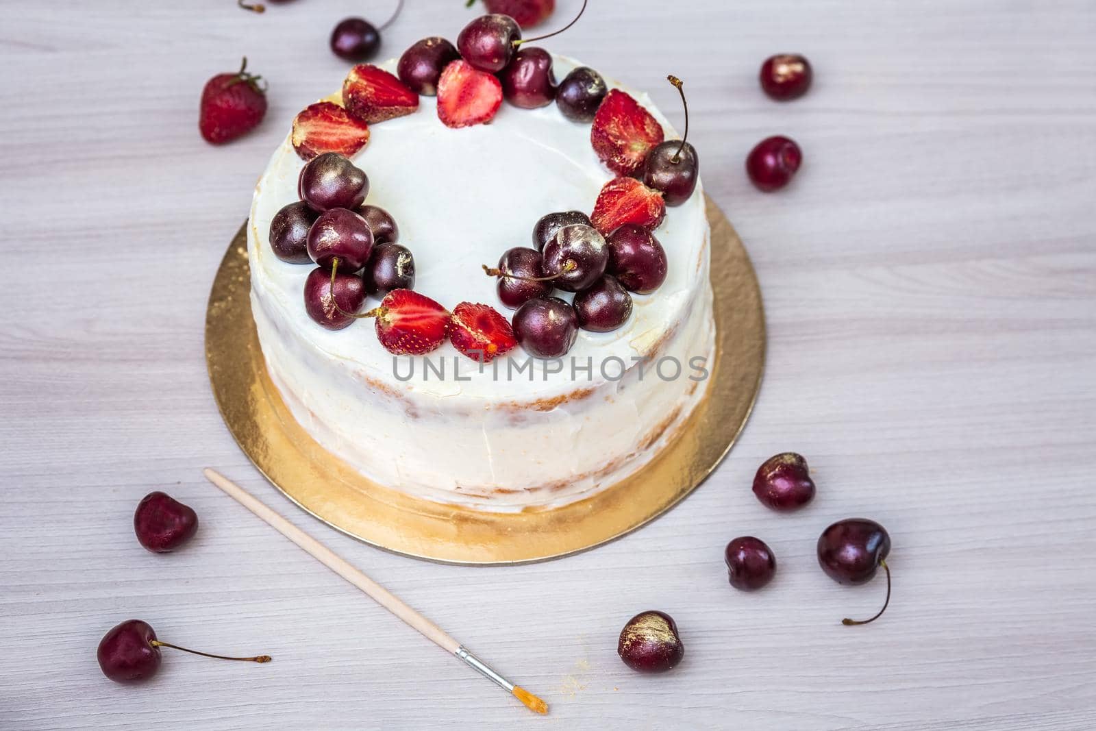 Cherries and strawberries with edible gold on top of cheesecake with coconut.