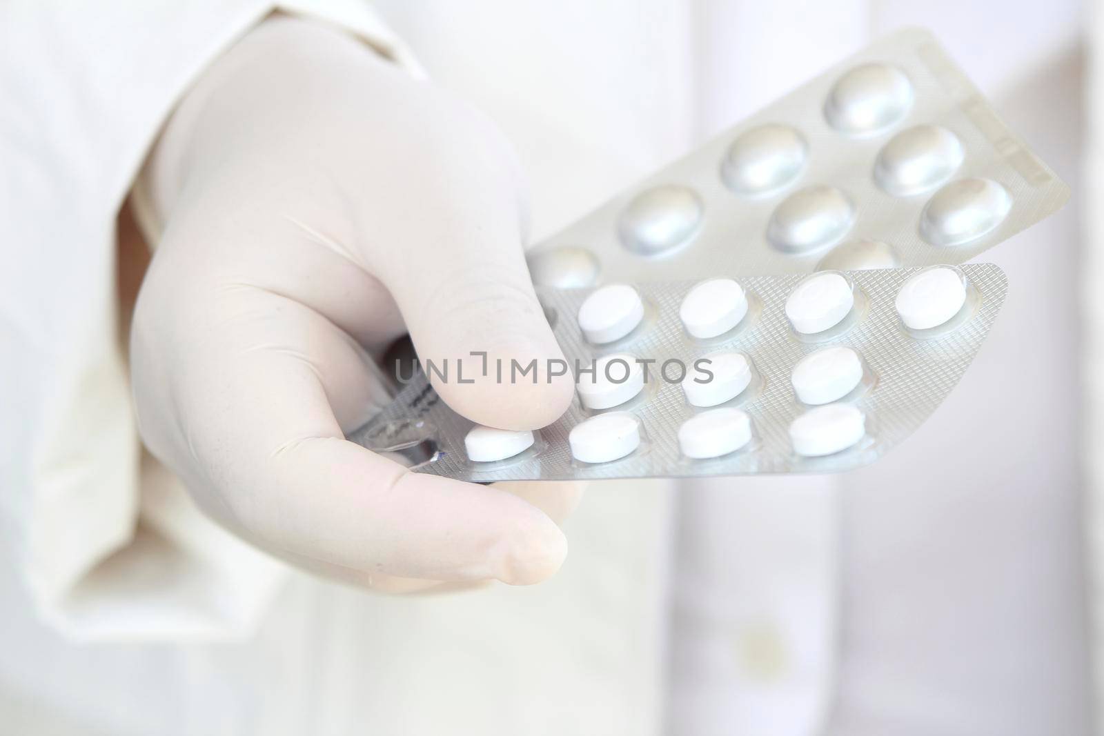 Male hand in white surgical glove holding pill blisters