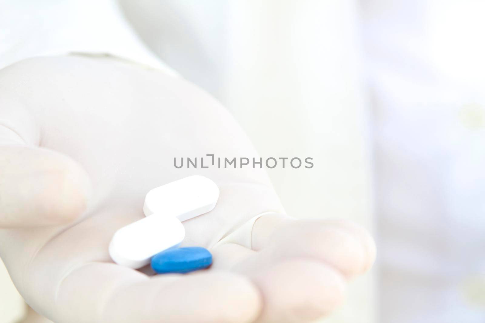 Male hand in white surgical glove holding pills