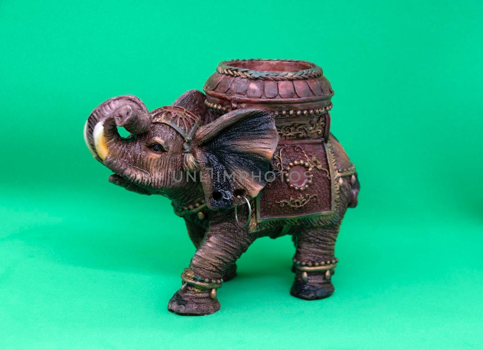 Figurine of an Indian elephant on a green background close-up. Candlestick in the shape of an Indian elephant.