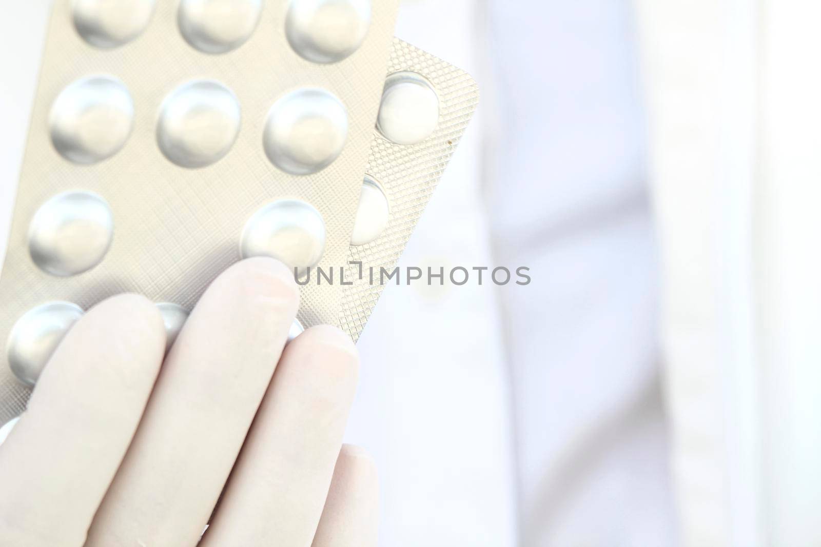 Male hand in white surgical glove holding pill blisters