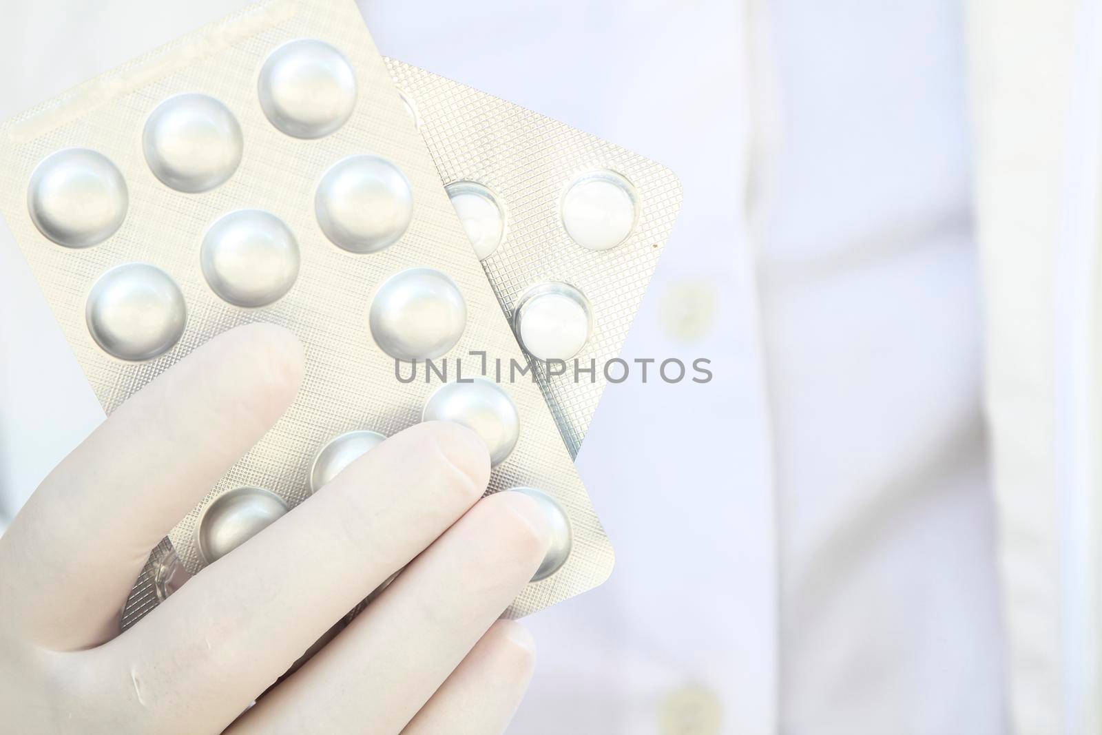 Male hand in white surgical glove holding pill blisters
