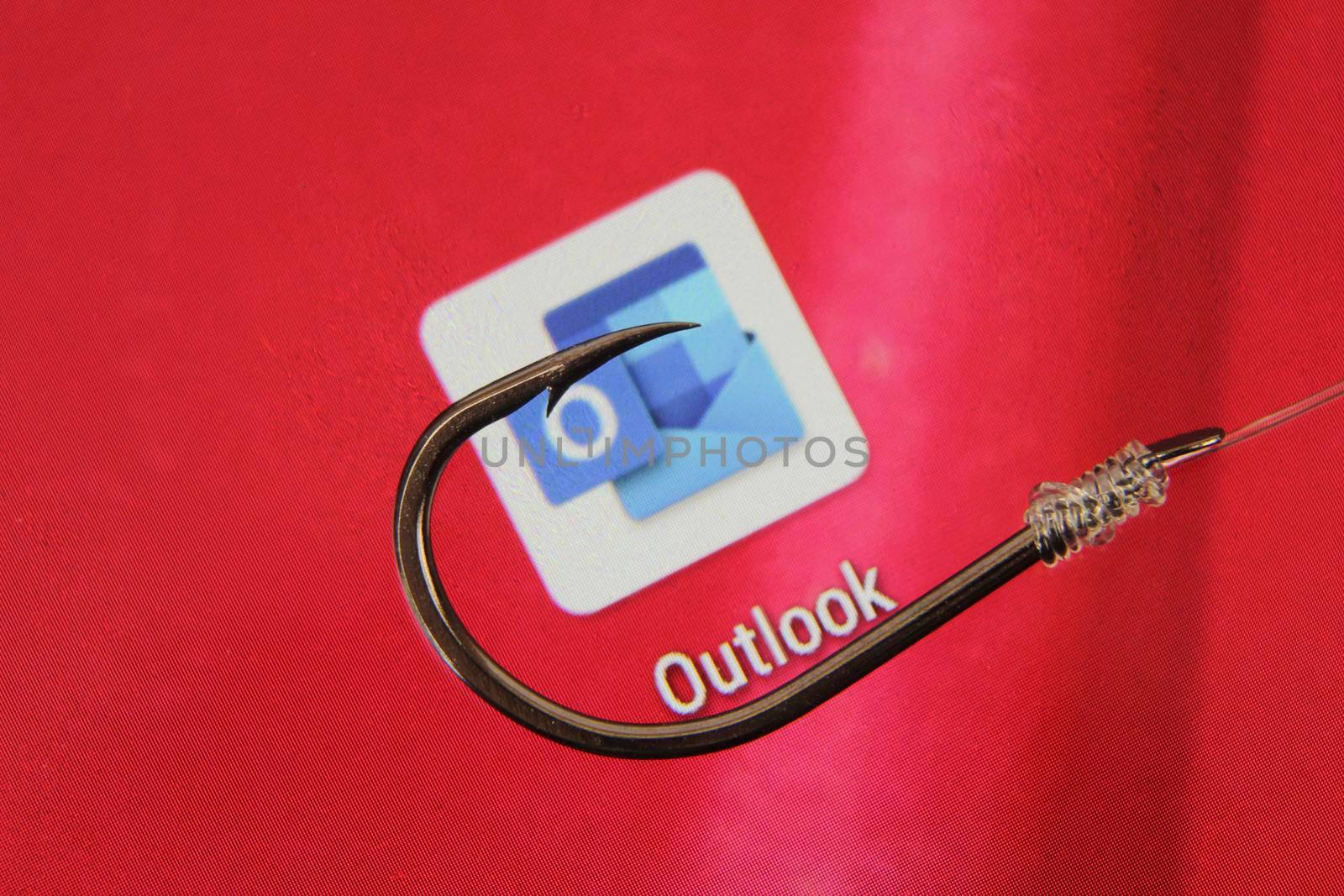 Madrid, Spain- May 10, 2010: Conceptual picture emulating phishing scam with a hook on Outlook icon on red screen