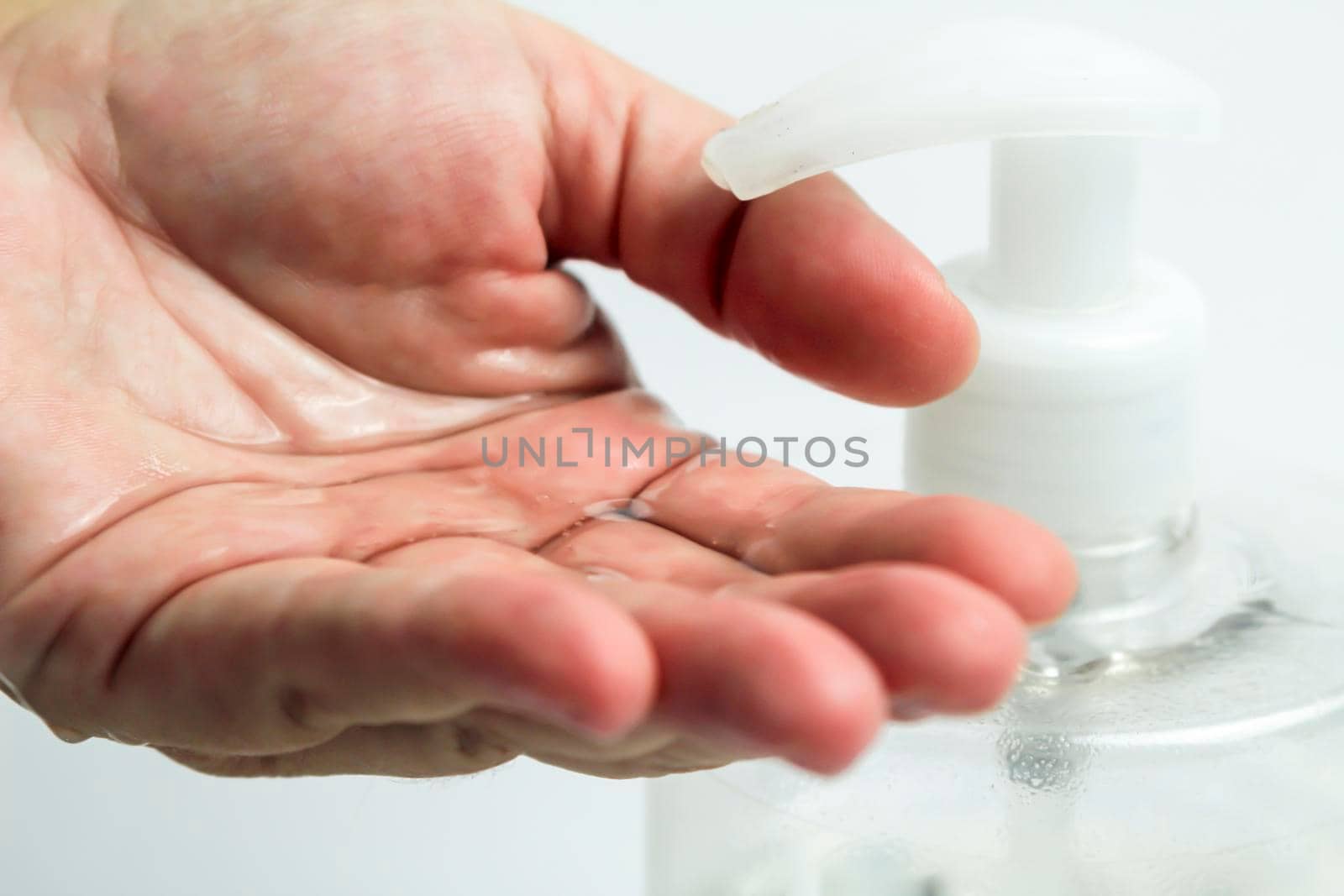 Hydroalcoholic gel bottle pouring gel into a hand on white background