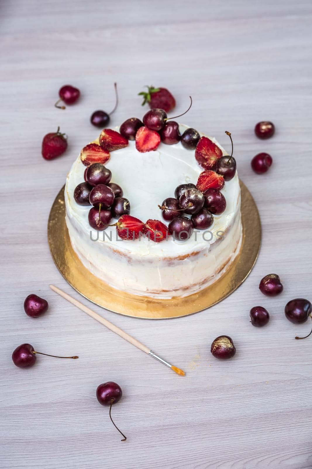 Cherries and strawberries with edible gold on top of cheesecake with coconut.