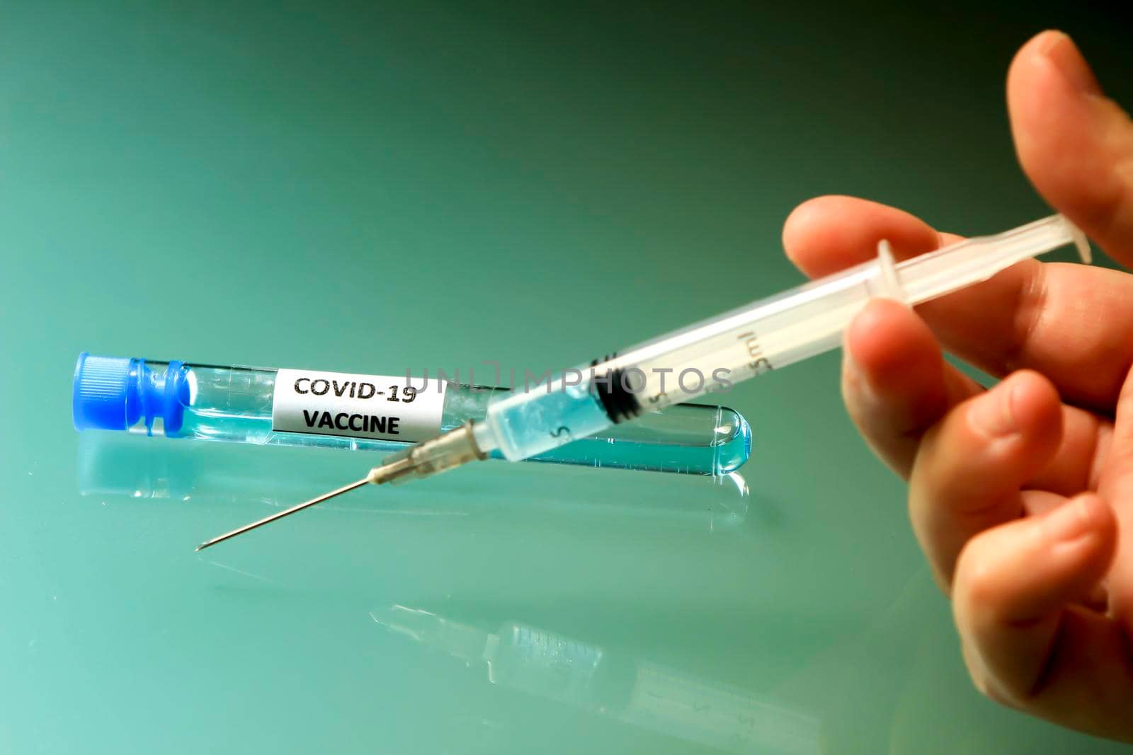 Hand holding Syringe next to test tube with vaccine for Covid-19 virus