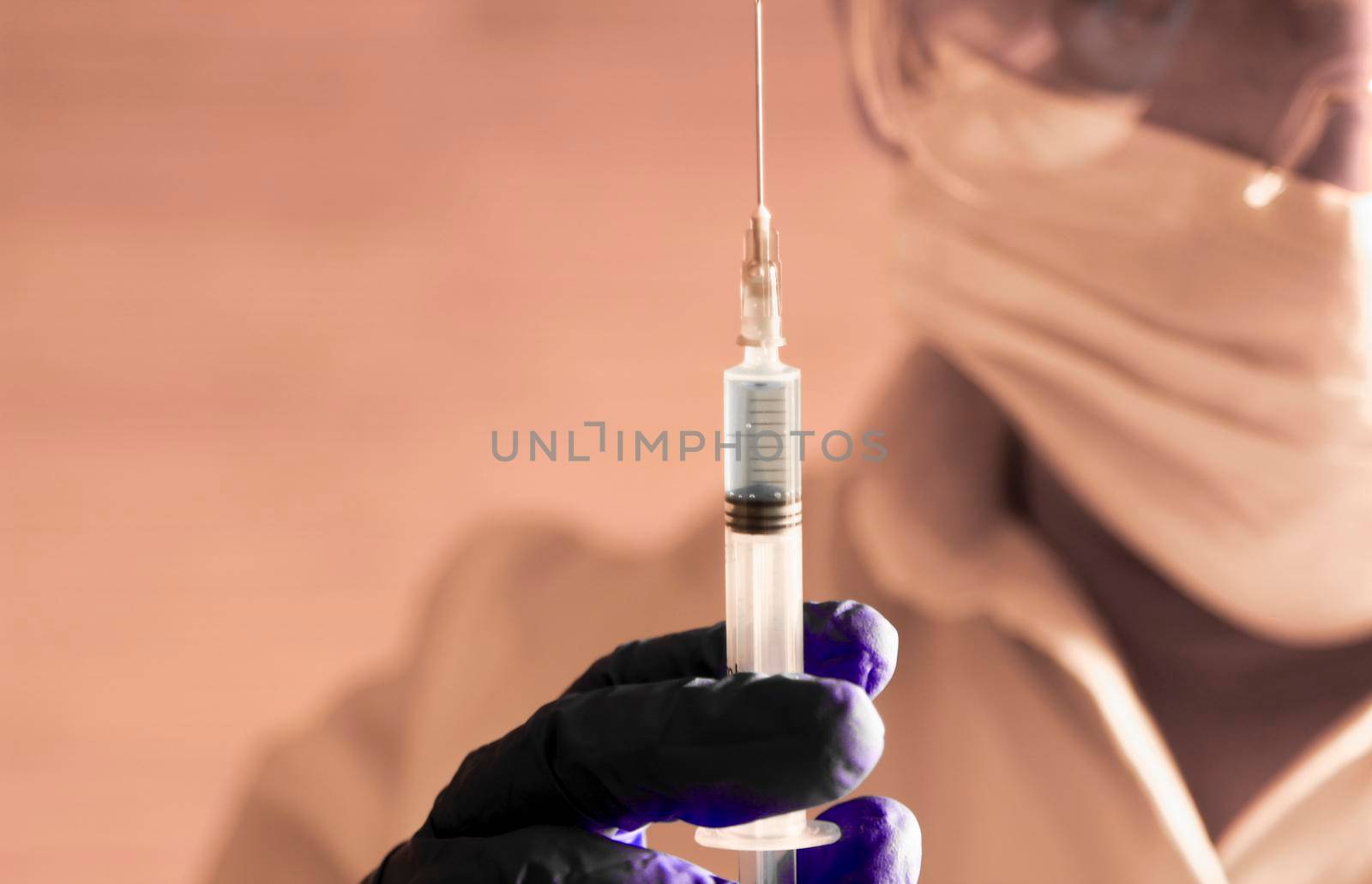 Laboratory assistant wearing protective glasses and surgery gloves holding a syringe with Covid-19 virus vaccine