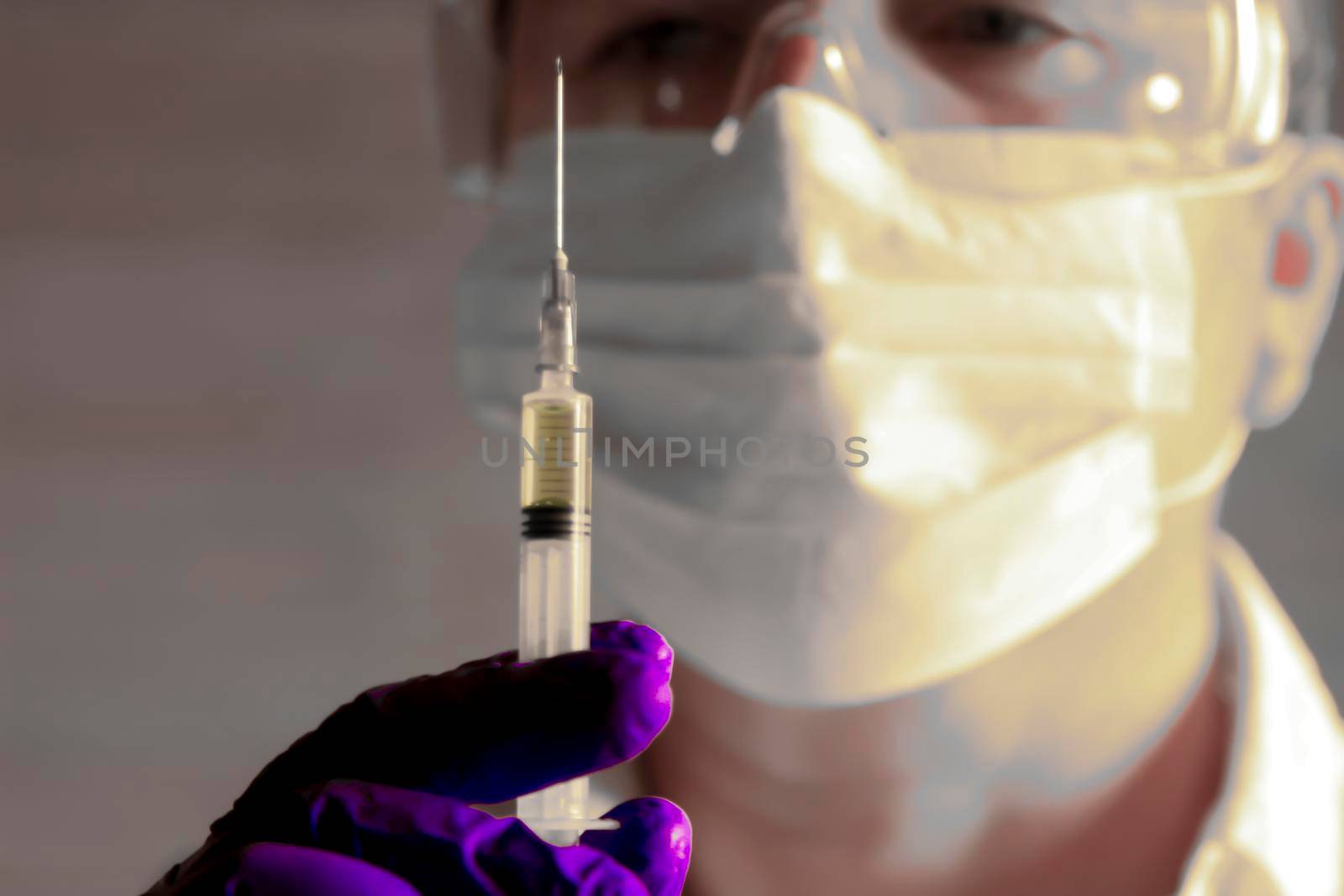 Laboratory assistant wearing protective glasses and surgery gloves holding a syringe with Covid-19 virus vaccine
