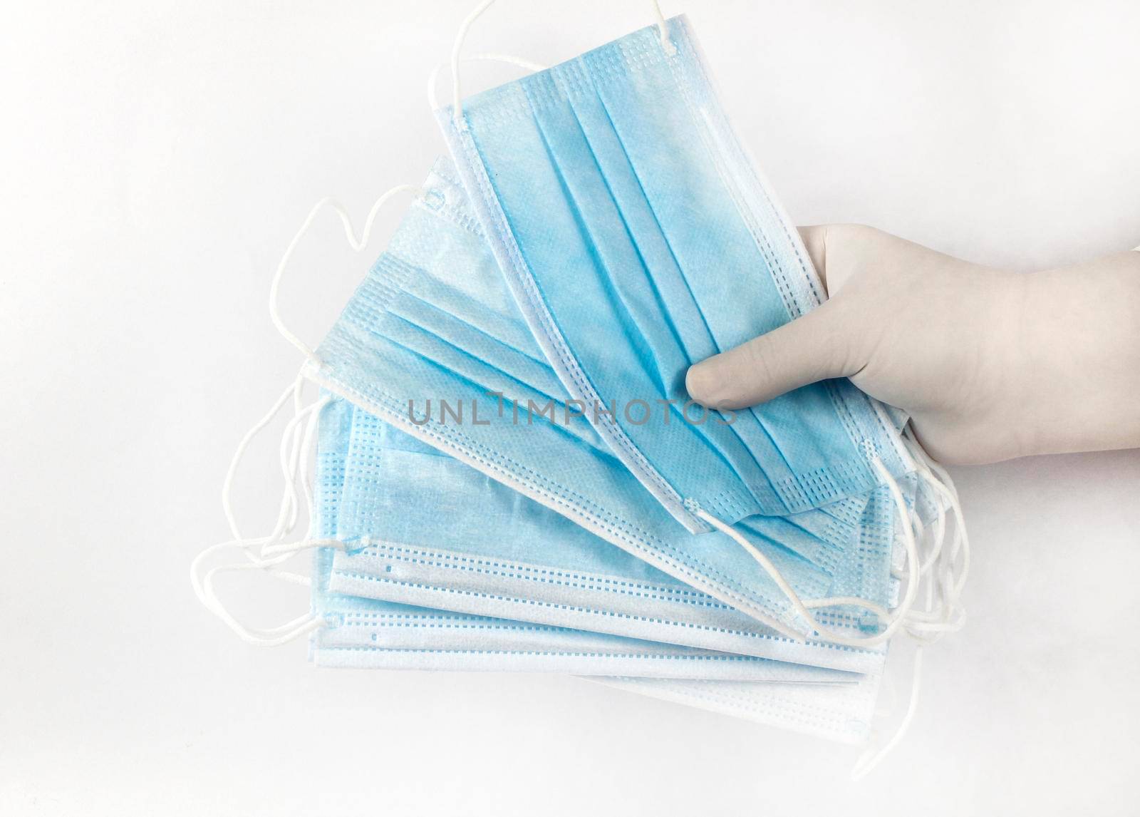 Hand on surgical gloves hanging Disposable Medical masks on white background. Covid-19 and healthcare concept