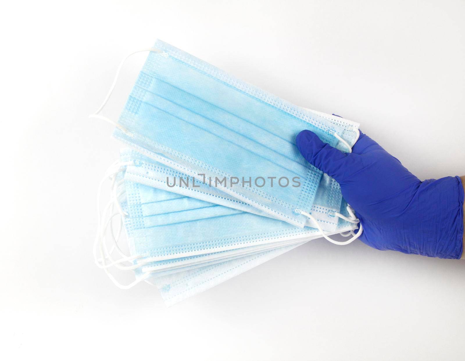 Hand on blue surgical gloves hanging Disposable Medical masks on white background. Covid-19 and healthcare concept