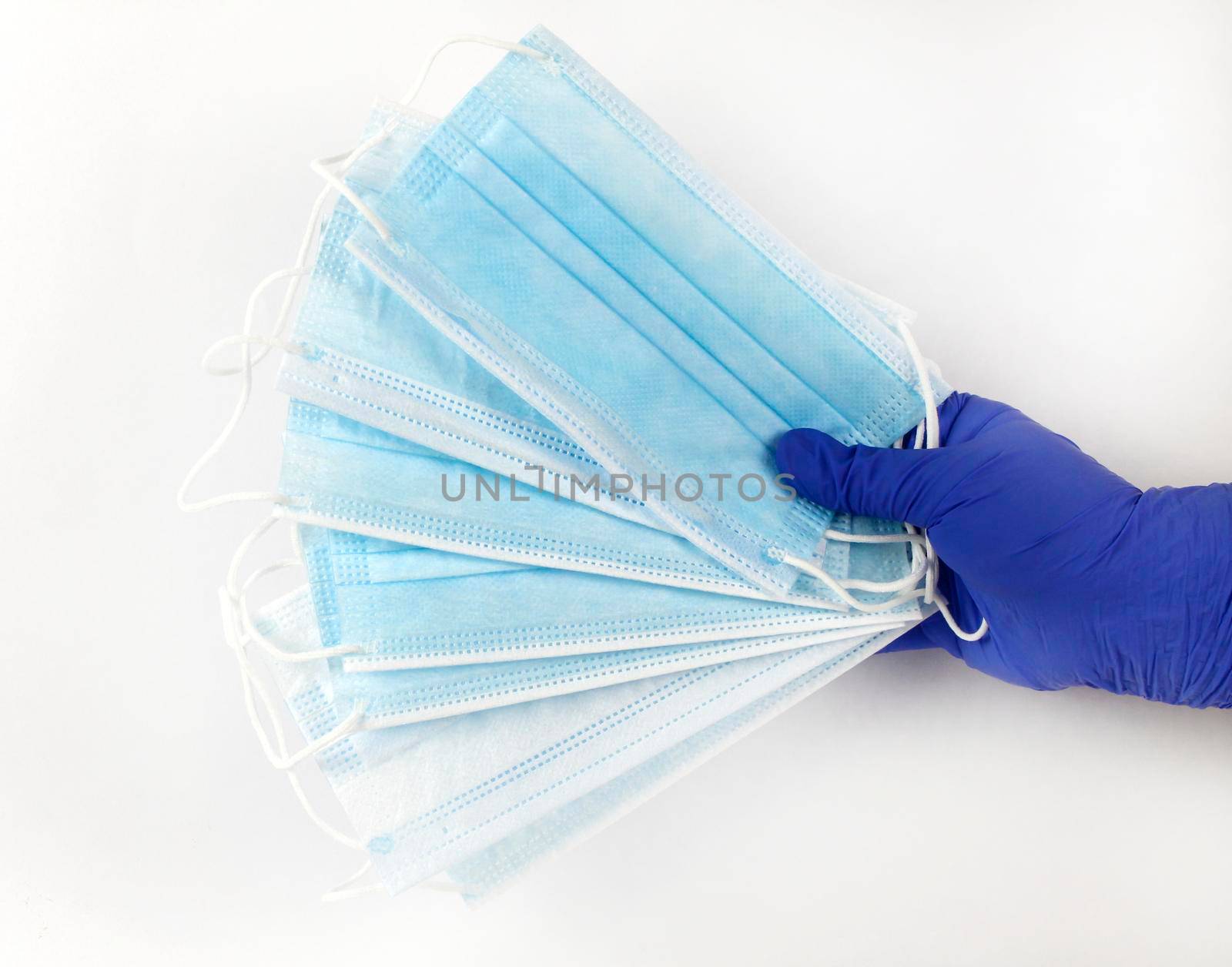 Hand on blue surgical gloves hanging Disposable Medical masks on white background. Covid-19 and healthcare concept
