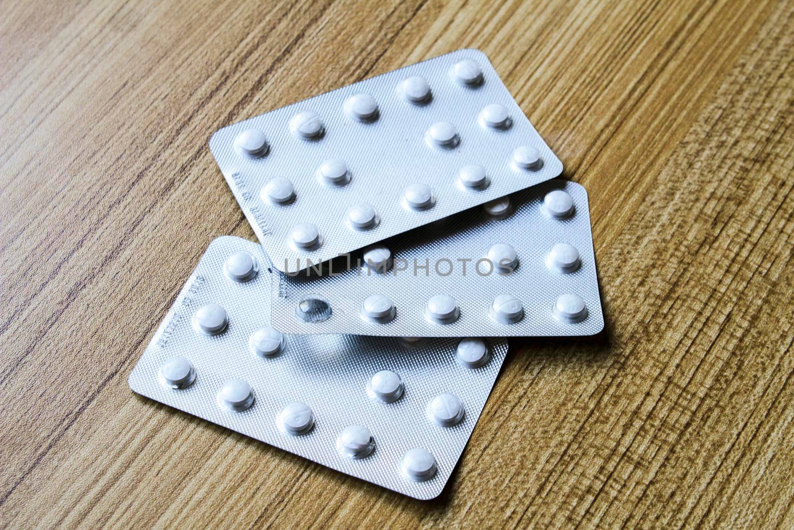 White pill blister packs on wooden table background