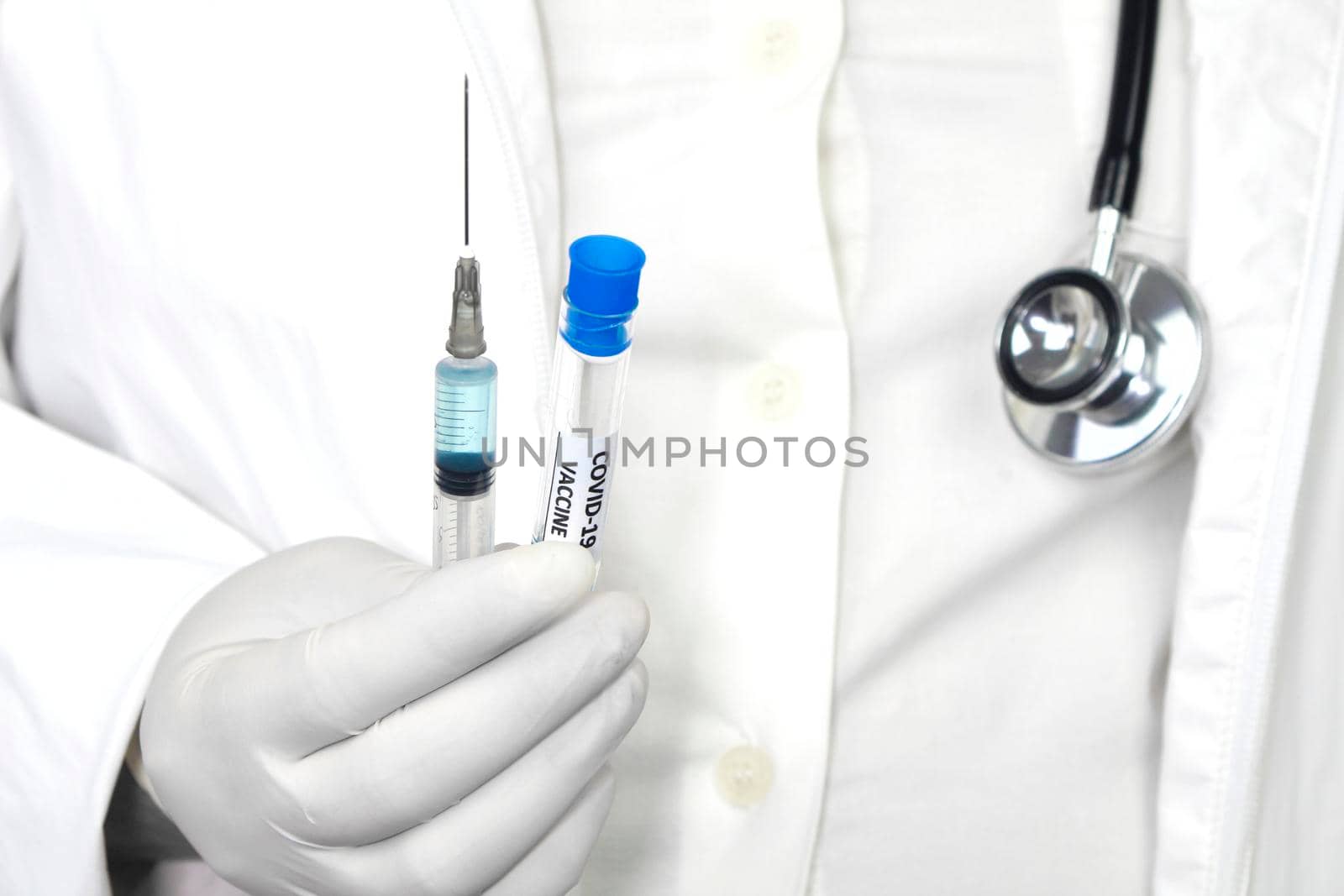 Medical professional on white uniform and surgery gloves holding a syringe with Covid-19 virus vaccine