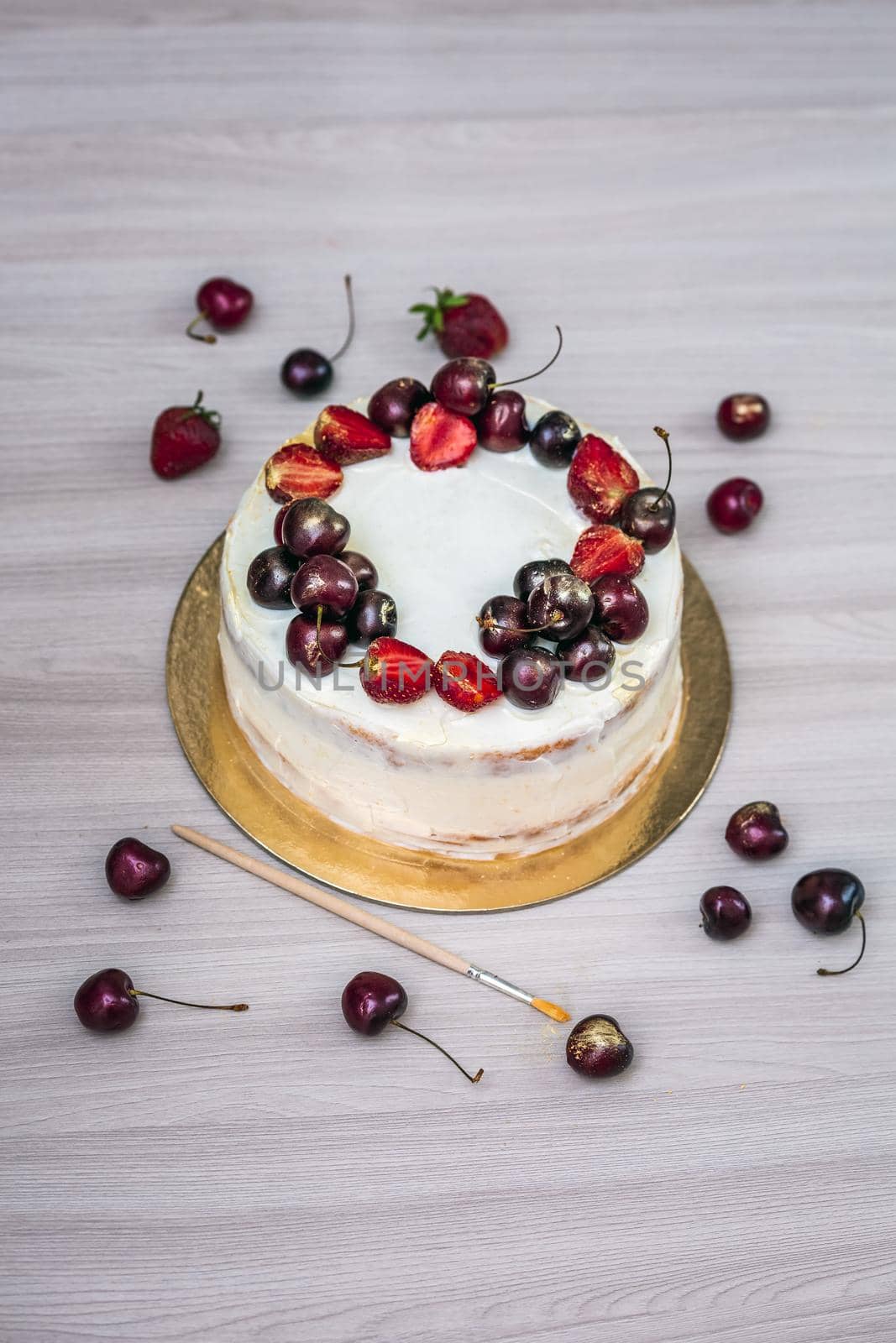 Cherries and strawberries with edible gold on top of cheesecake with coconut.