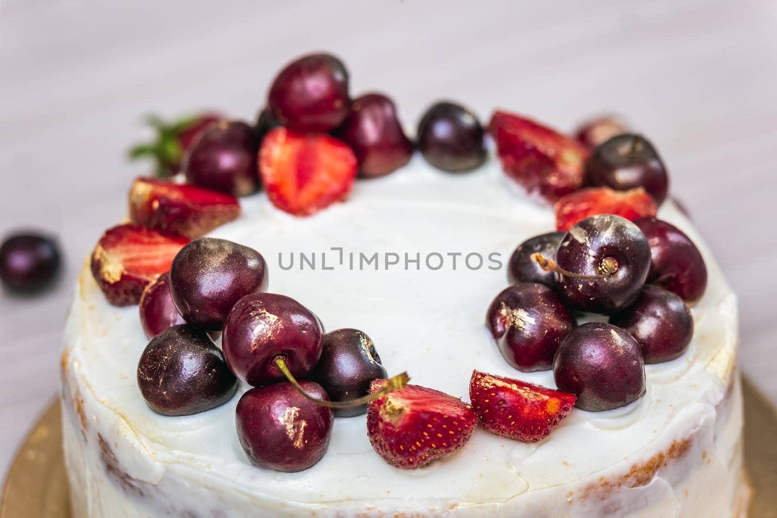Cherries and strawberries with edible gold on top of cheesecake with coconut.