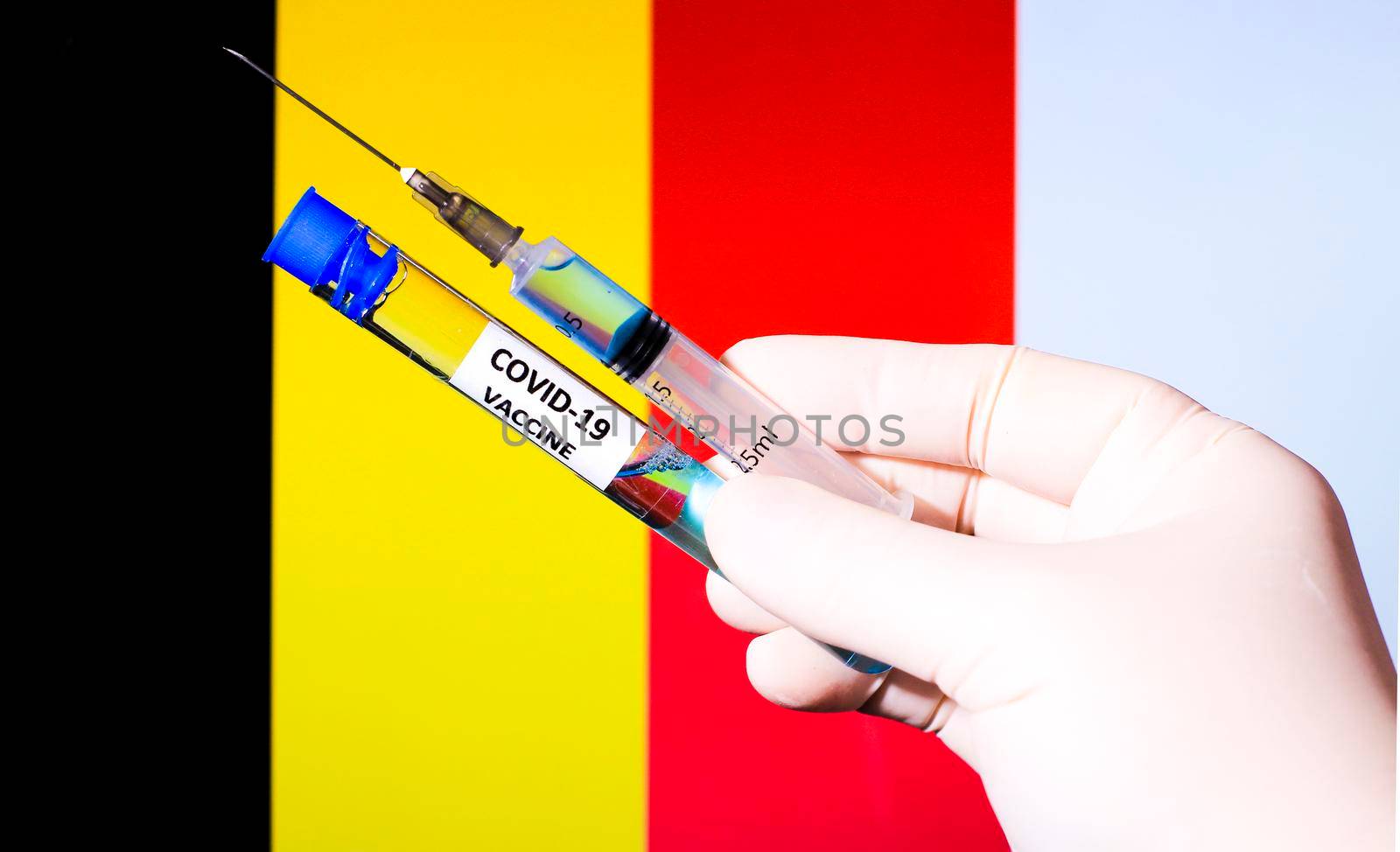 Hand in surgery glove holding syringe with covid vaccine. Belgian flag in the background