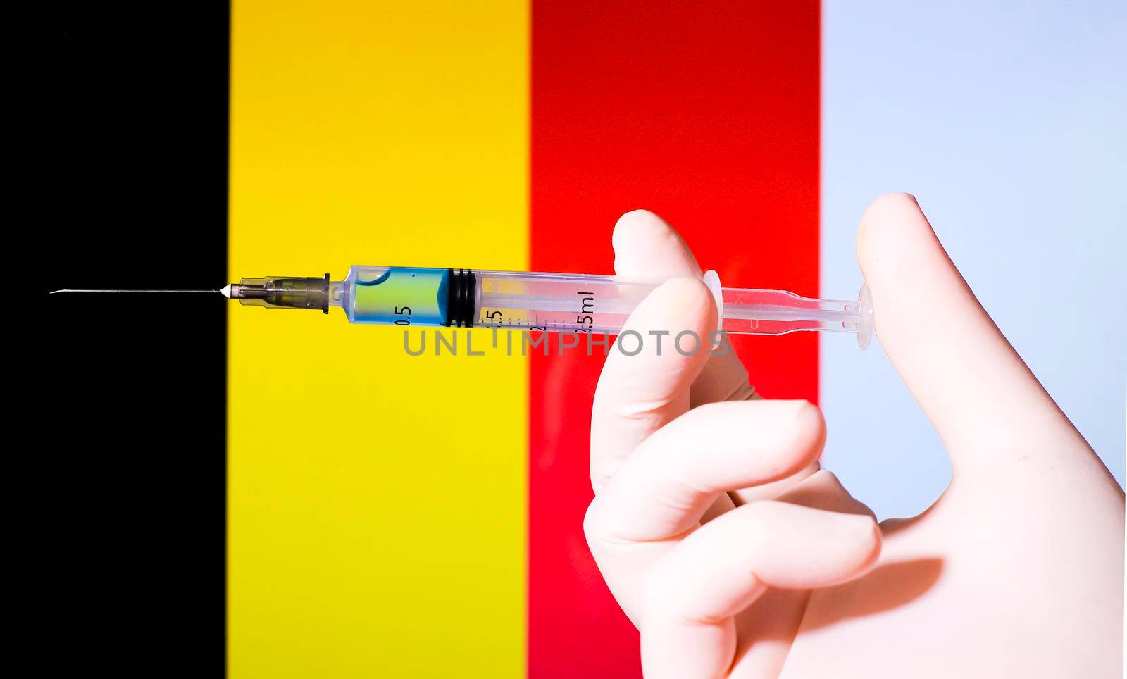Hand in surgery glove holding syringe with covid vaccine. Belgian flag in the background