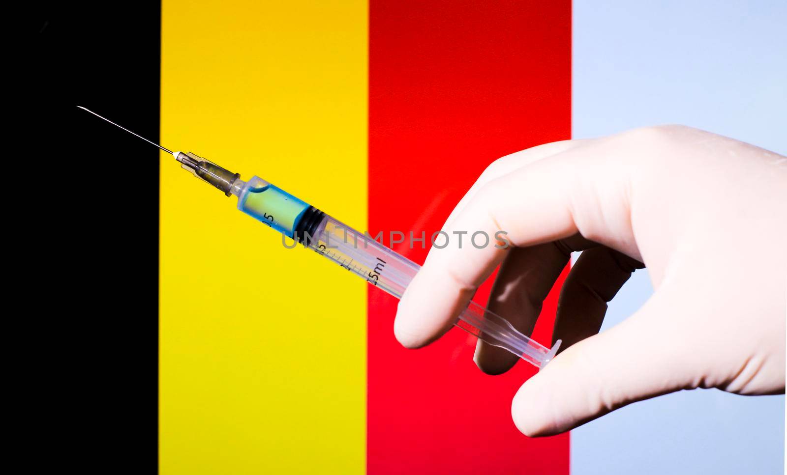 Hand in surgery glove holding syringe with covid vaccine. Belgian flag in the background