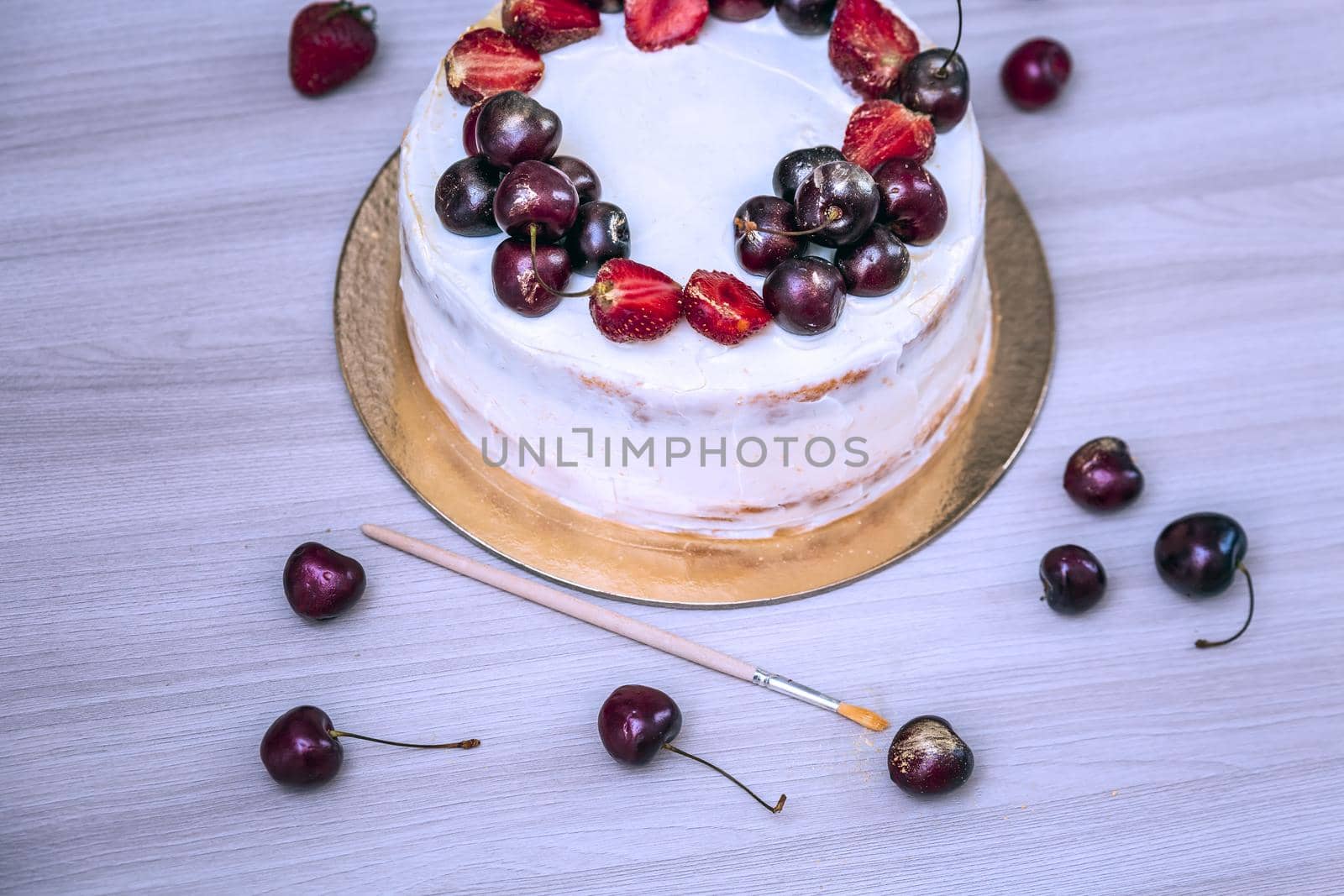 Cherries and strawberries with edible gold on top of cheesecake with coconut. Blue toning.
