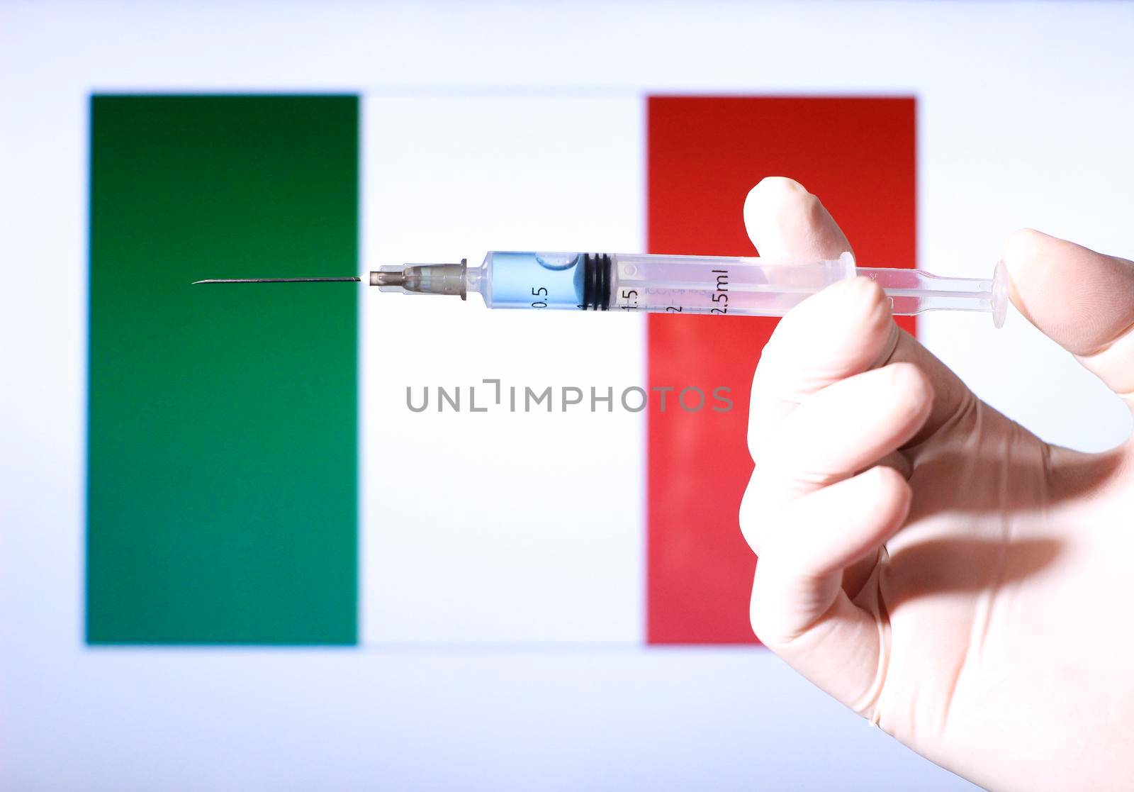 Hand in surgery glove holding syringe with covid vaccine. Italian flag in the background