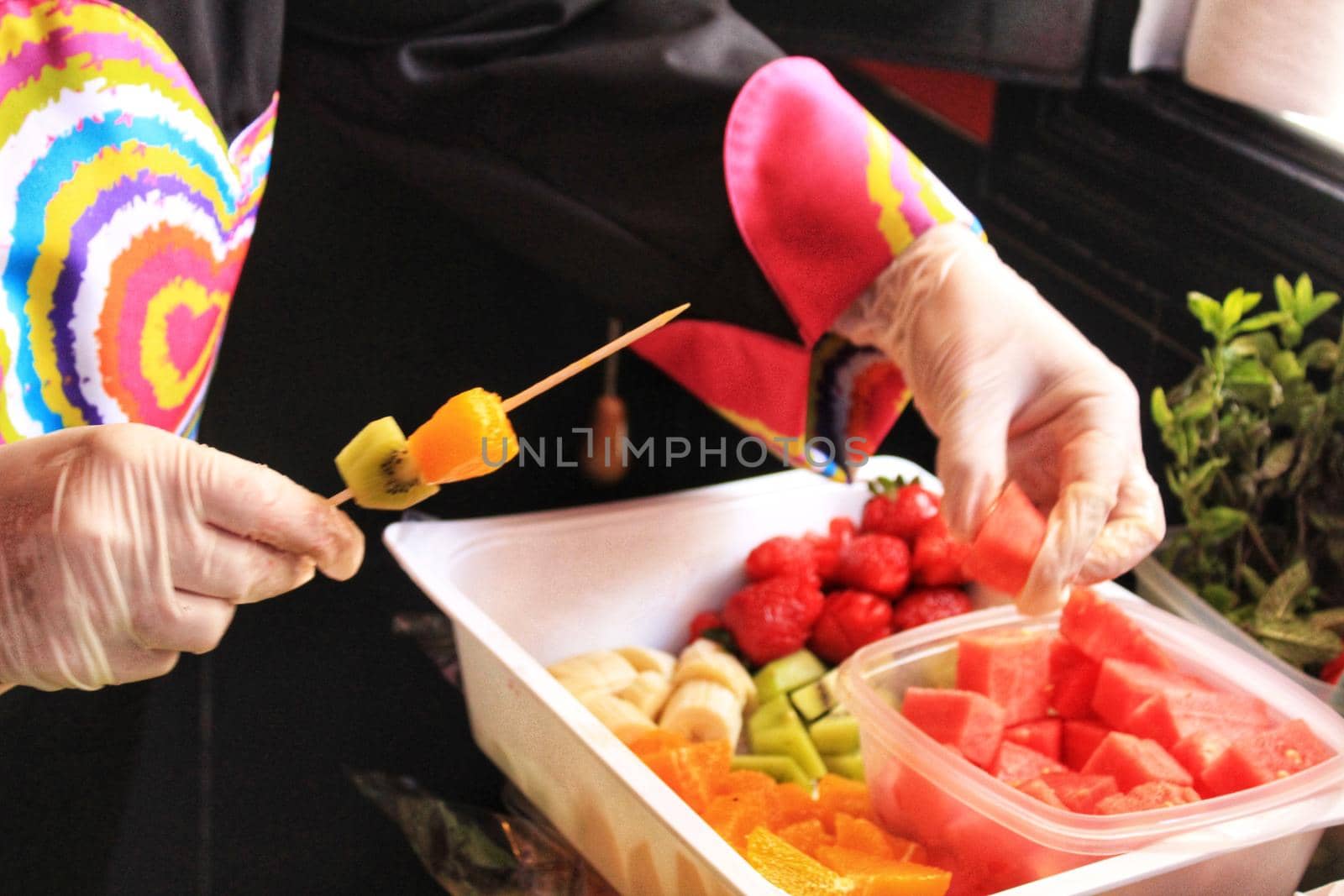 Cook hands with gloves preparing fruit skewers by soniabonet