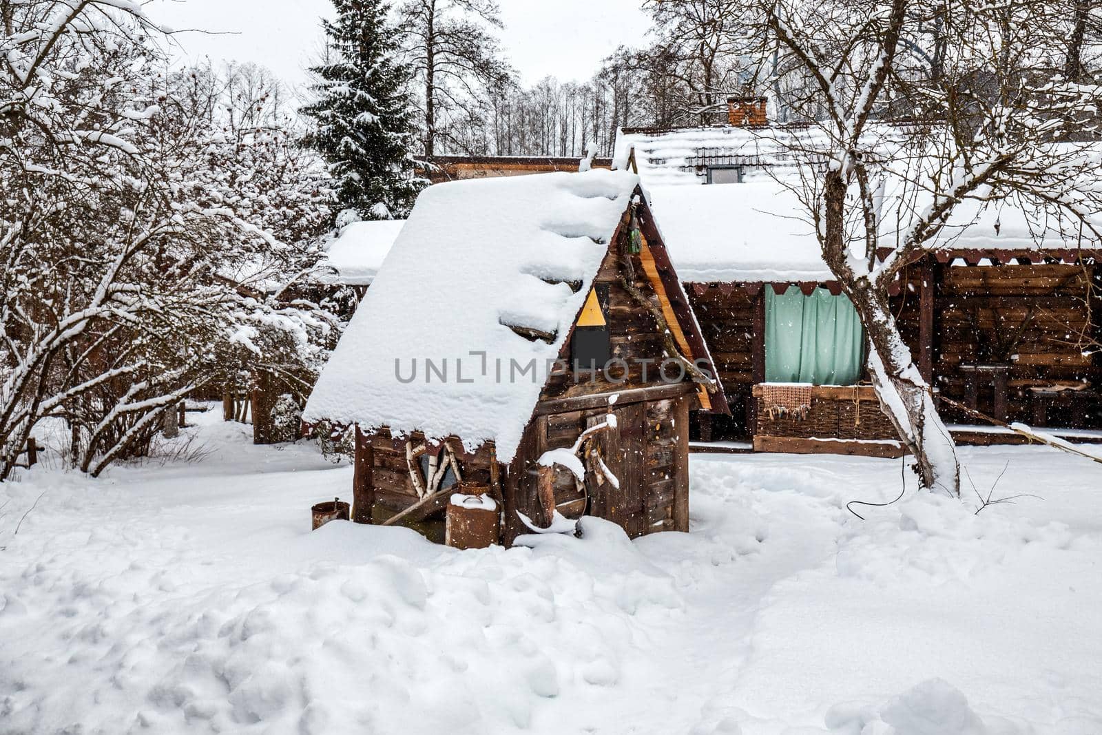 Decorated wooden house with textured wall covered with a heavy snow in the village in Belarus.