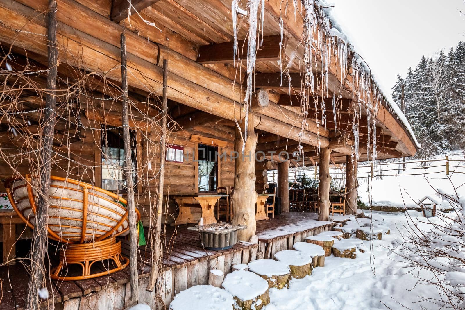 Decorated wooden house with textured wall covered with a heavy snow in the village in Belarus.