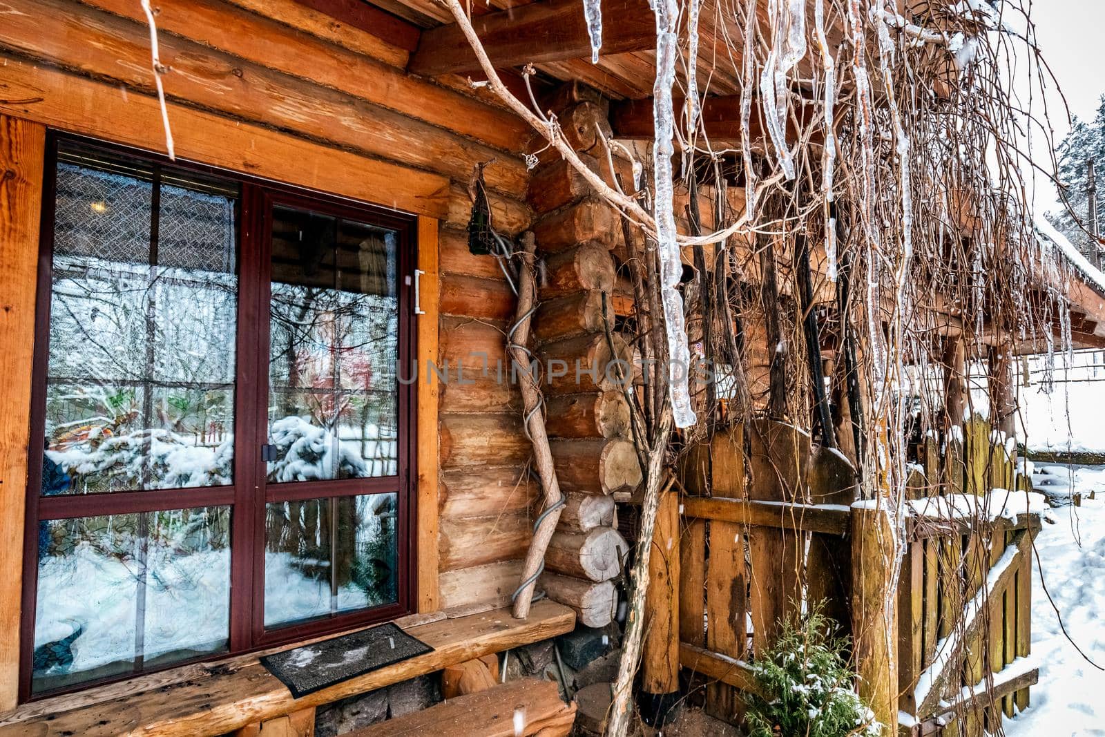 Decorated wooden house with textured wall covered with a heavy snow in the village in Belarus.