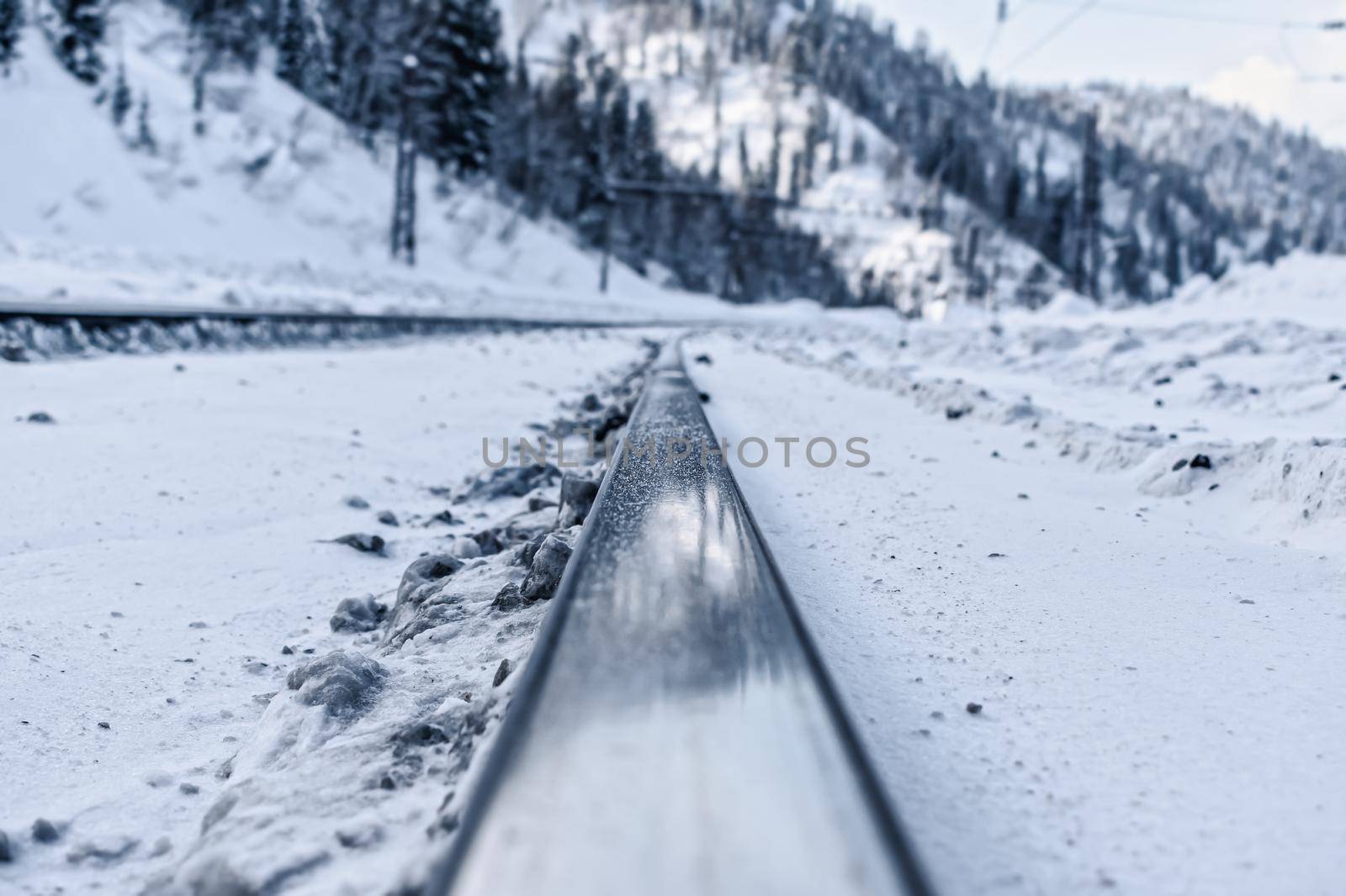 Railroad rails close up on the background of snowy mountains in winter