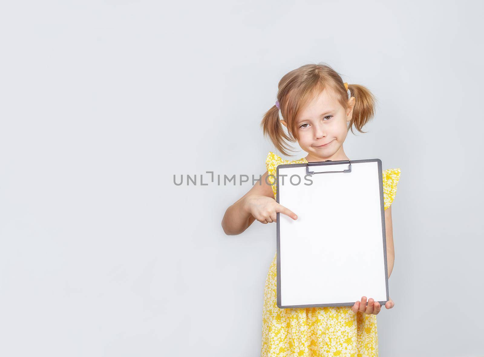 Little Caucasian girl holding a clipboard with a blank paper with copy space by galinasharapova