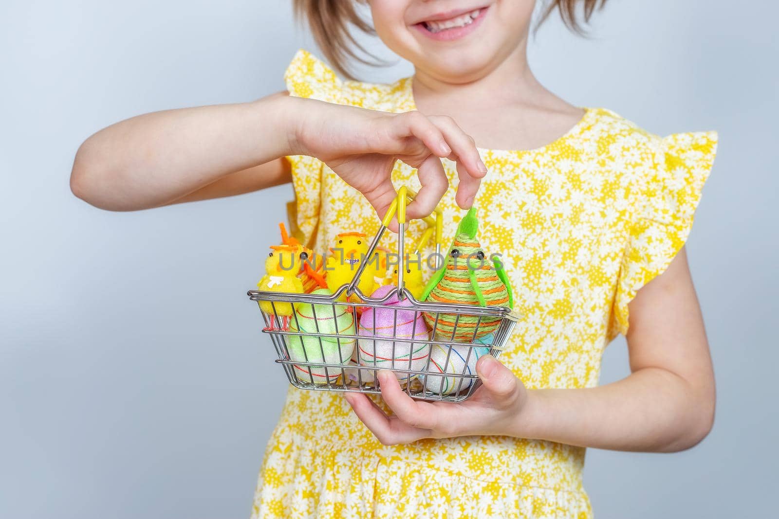 Cropped photo of girl with a shopping basket filled with Easter decorations. Easter background with place to insert text.