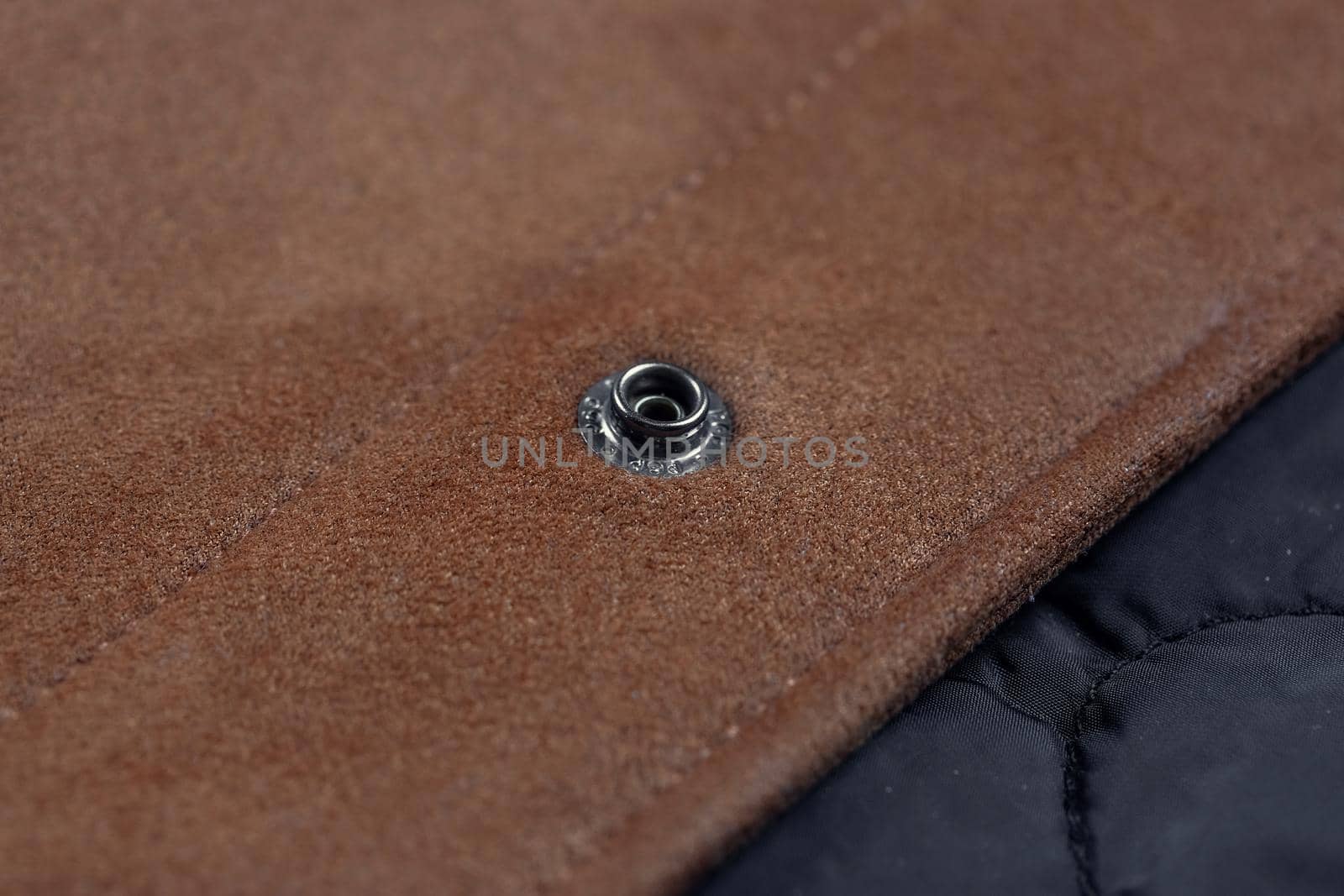 Close-up of a button-down button on a faux suede jacket.