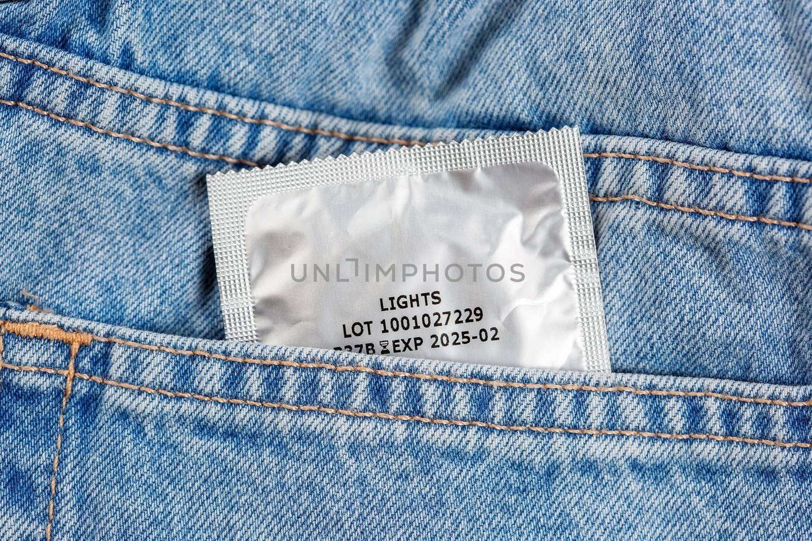 Close-up of a pocket of blue jeans from which a condom sticks out by galinasharapova