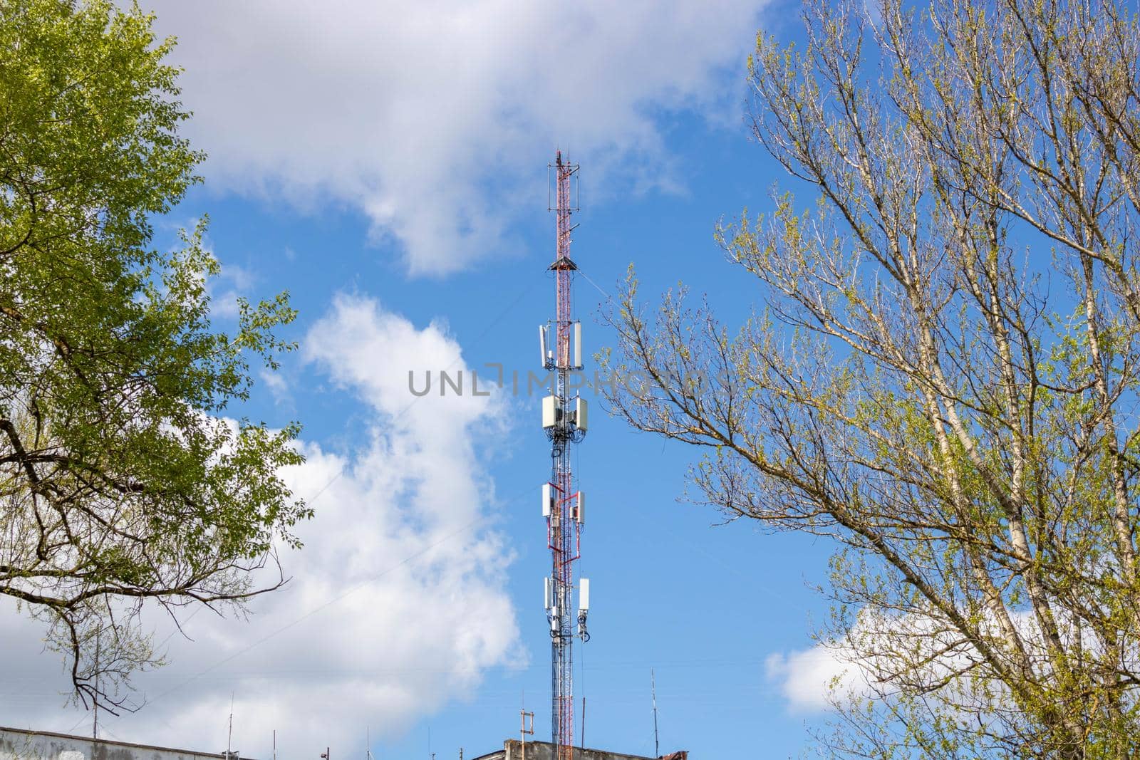 Cellular network or mobile antenna in the roof of a building, on cloudy sky.