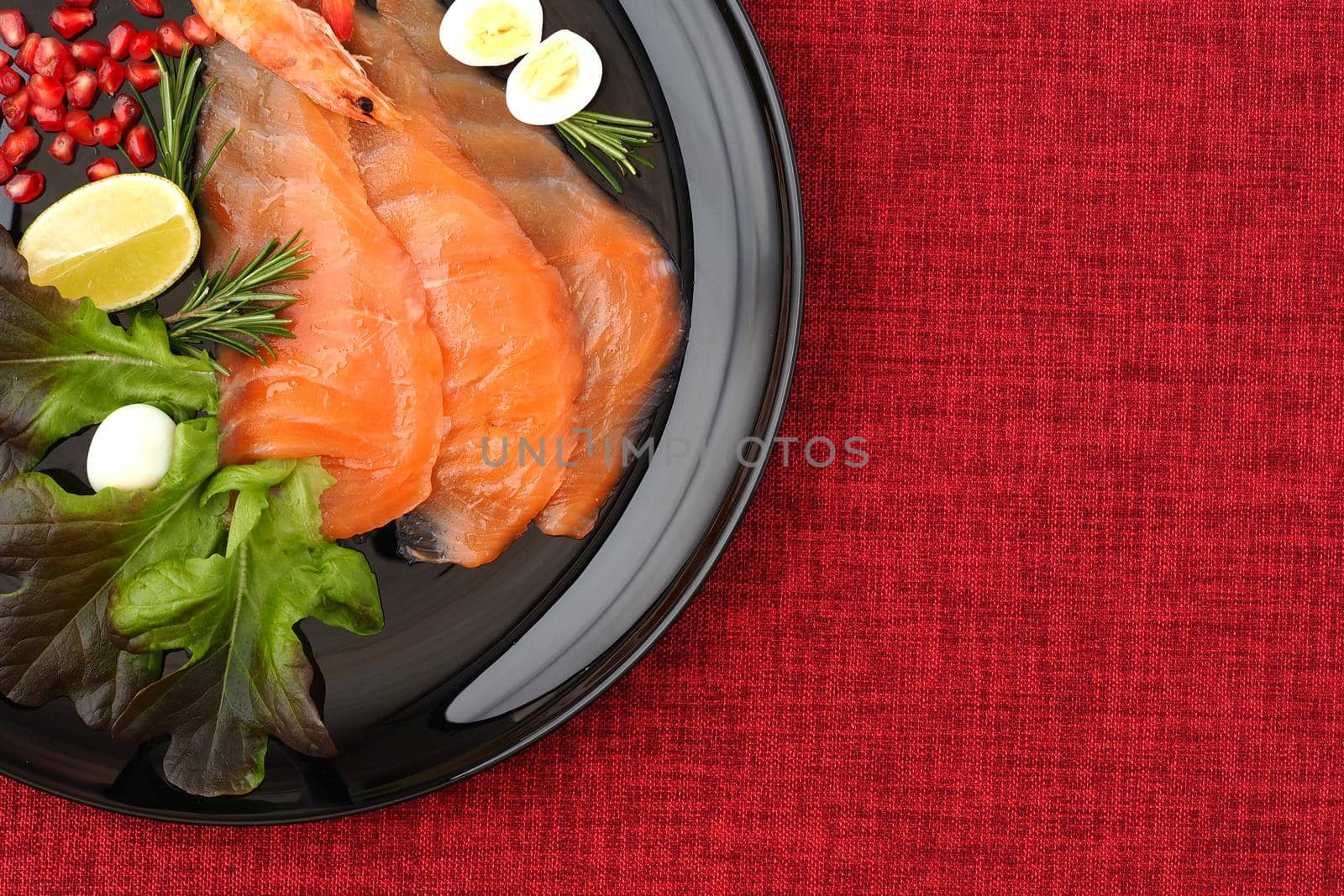 Fled lei. Red fish slices on a black plate with lemon and rosemary. by Olga26