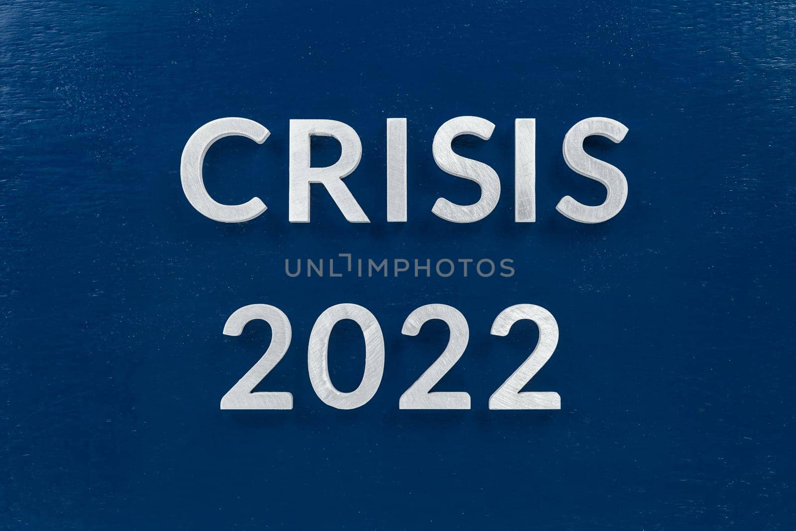 the words crisis 2022 laid with luminium letters on blue painted board background