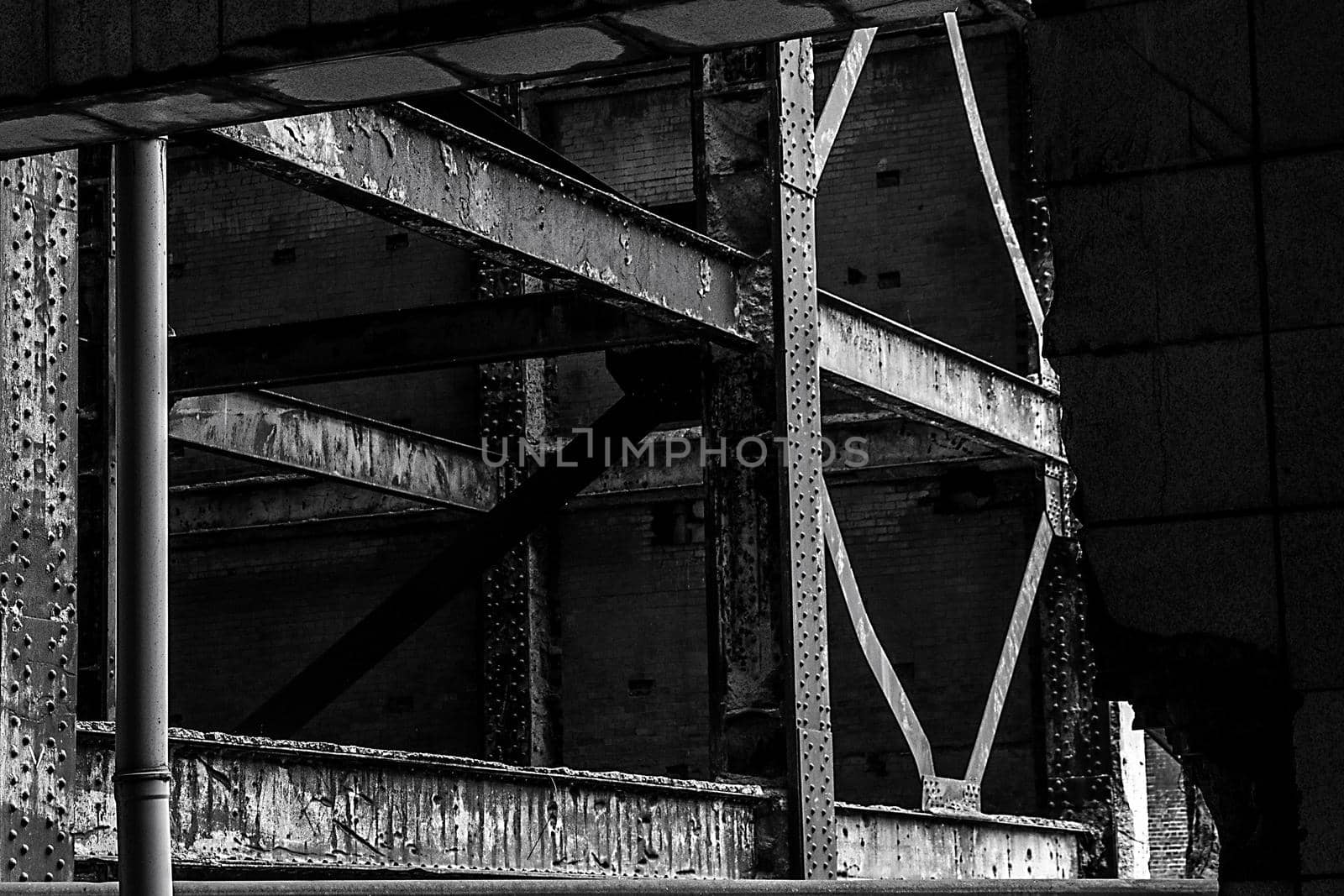 Close-up of the beams of an old rusty metal frame through a hole in a wall inside a derelict building