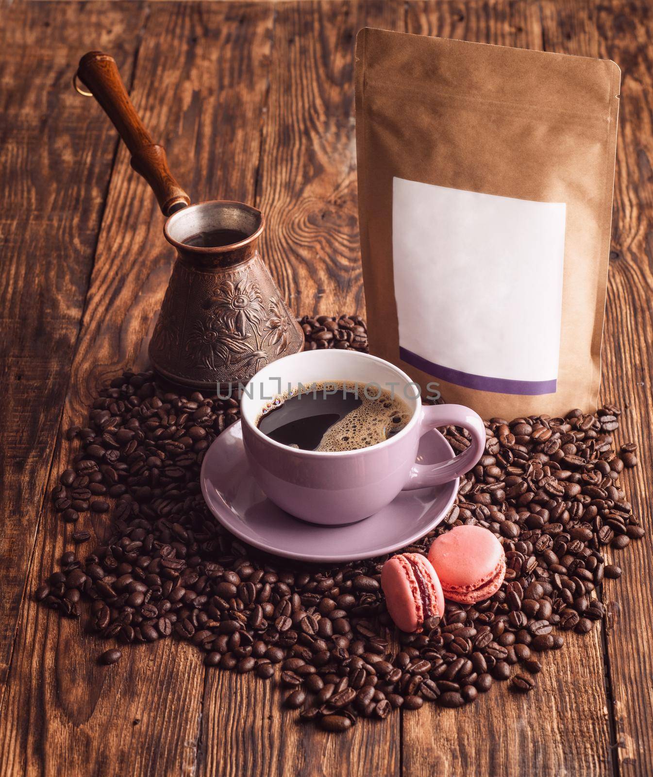 purple cup of coffee, macaroons, beans, turkish coffee pot, and craft paper pouch bag on wooden backgroun