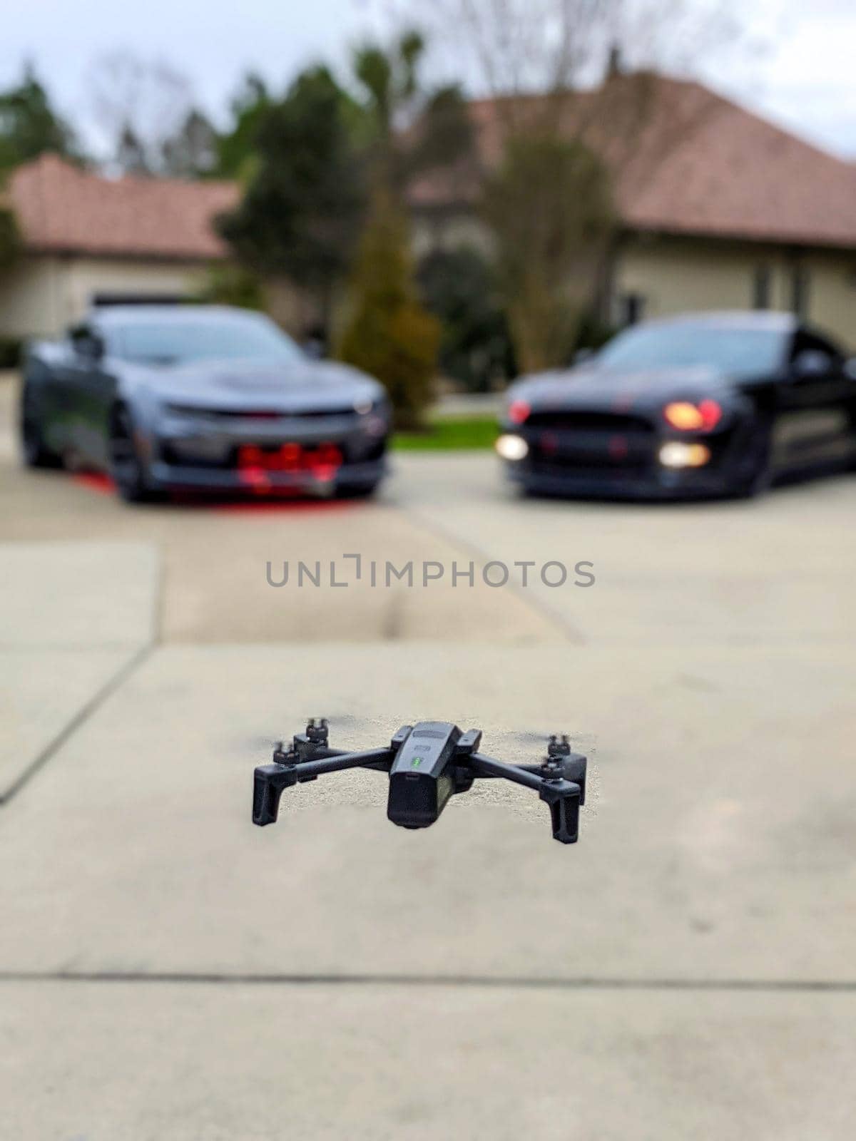 selective view of drone with bokeh of two sports cars beyond