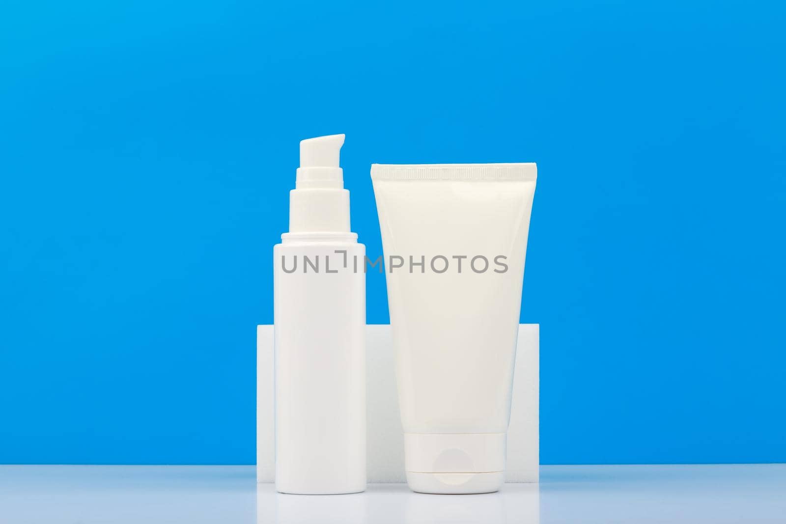 Set of two creams in white unbranded tube on white table against blue background with copy space. Concept of hygiene and hydrating and moisturizing beauty products, cream, balm or lotion