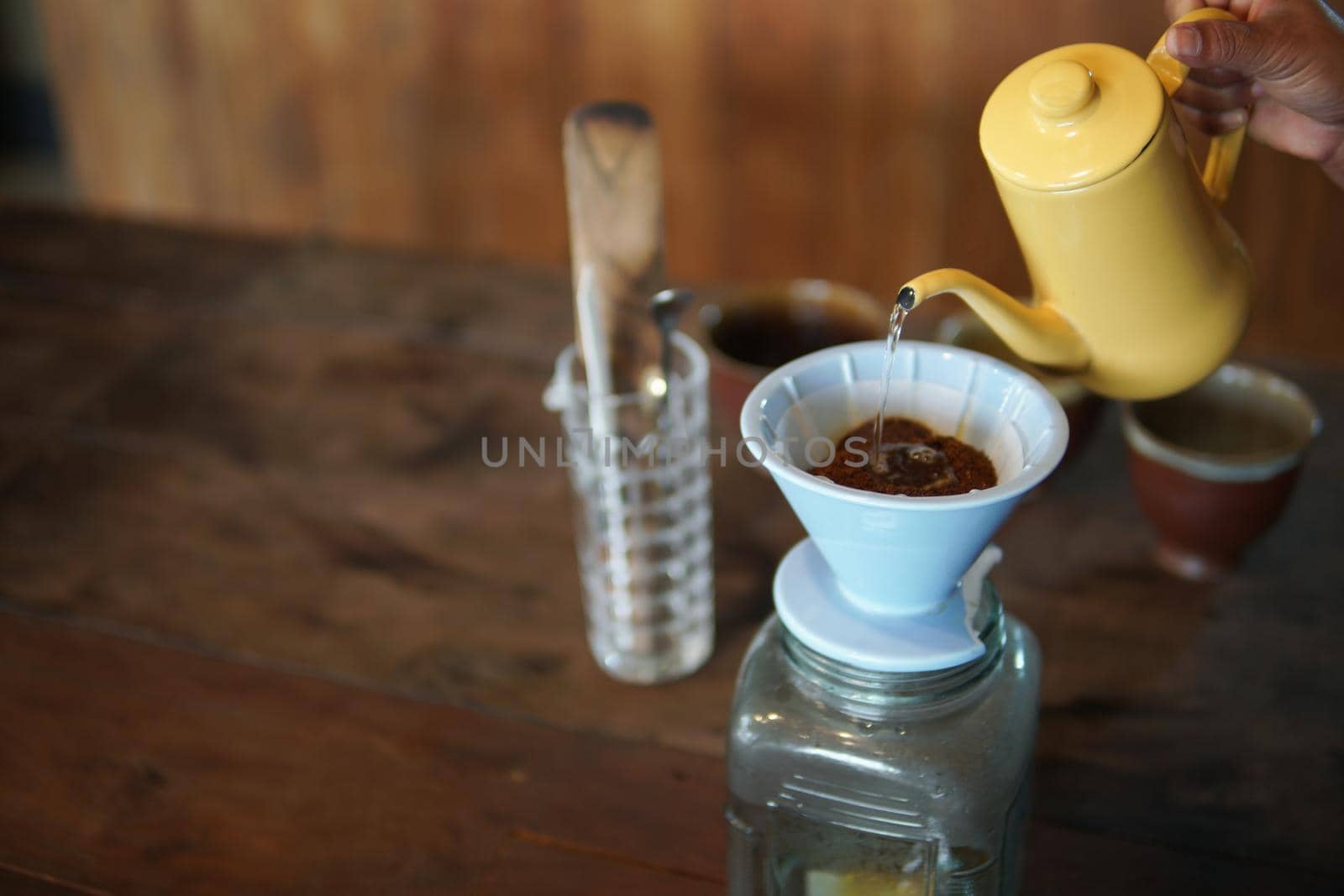 barista preparing brewing coffee with coffee maker and drip kettle. Dripping ground coffee with filter