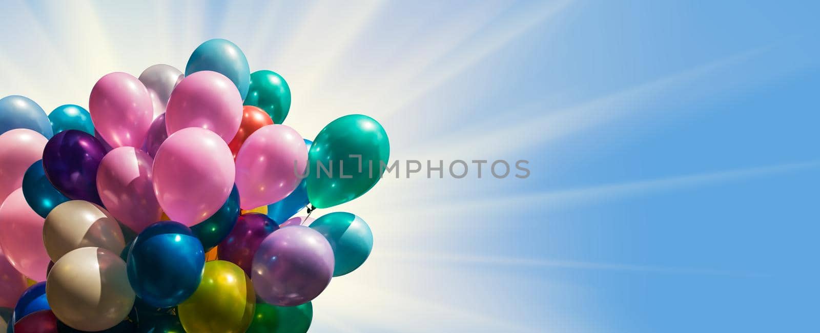 Bunch of colorful balloons against blue sky with sun light